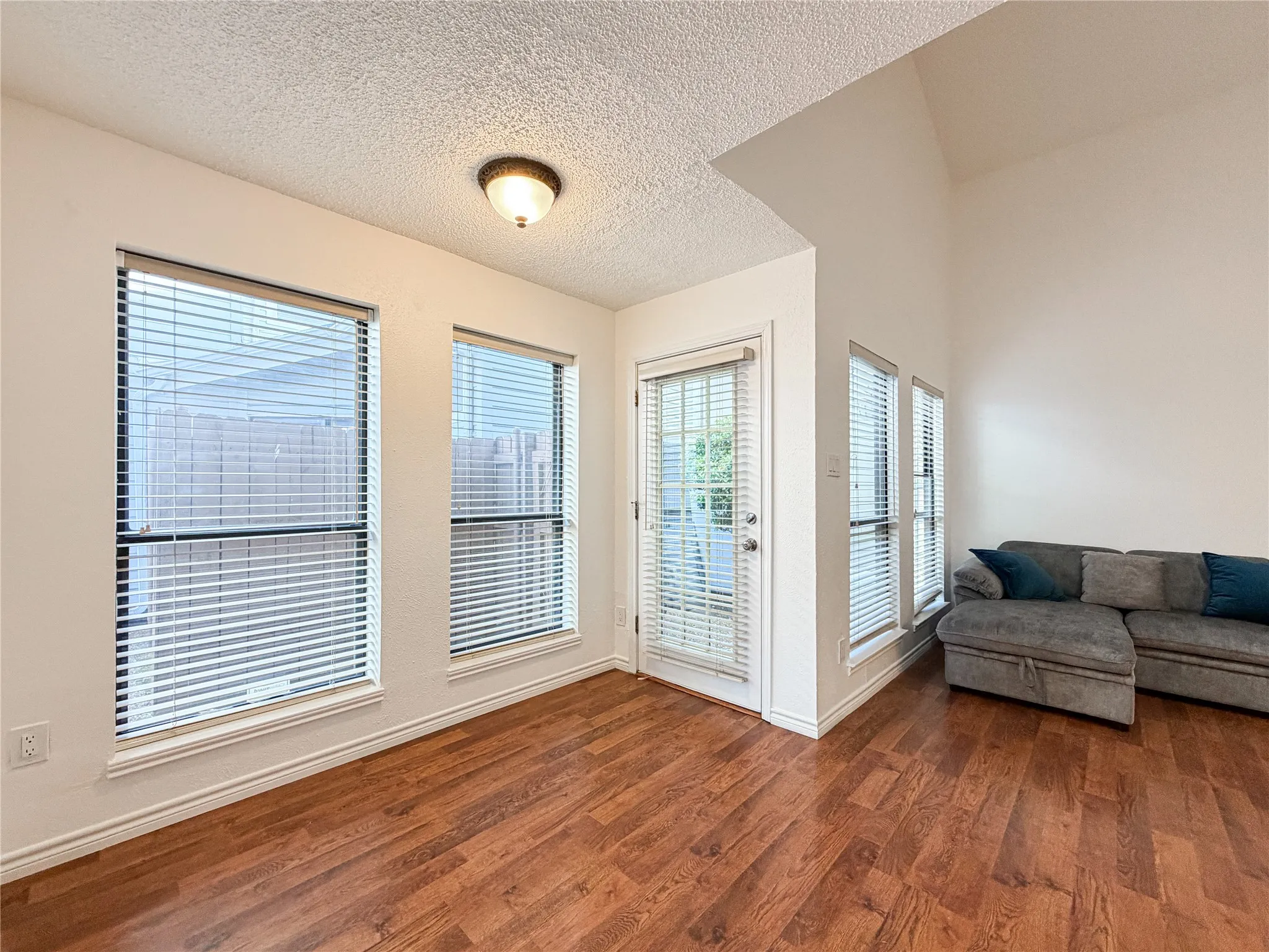 Vaulted ceiling, wood-finish flooring, multiple windows, French door access