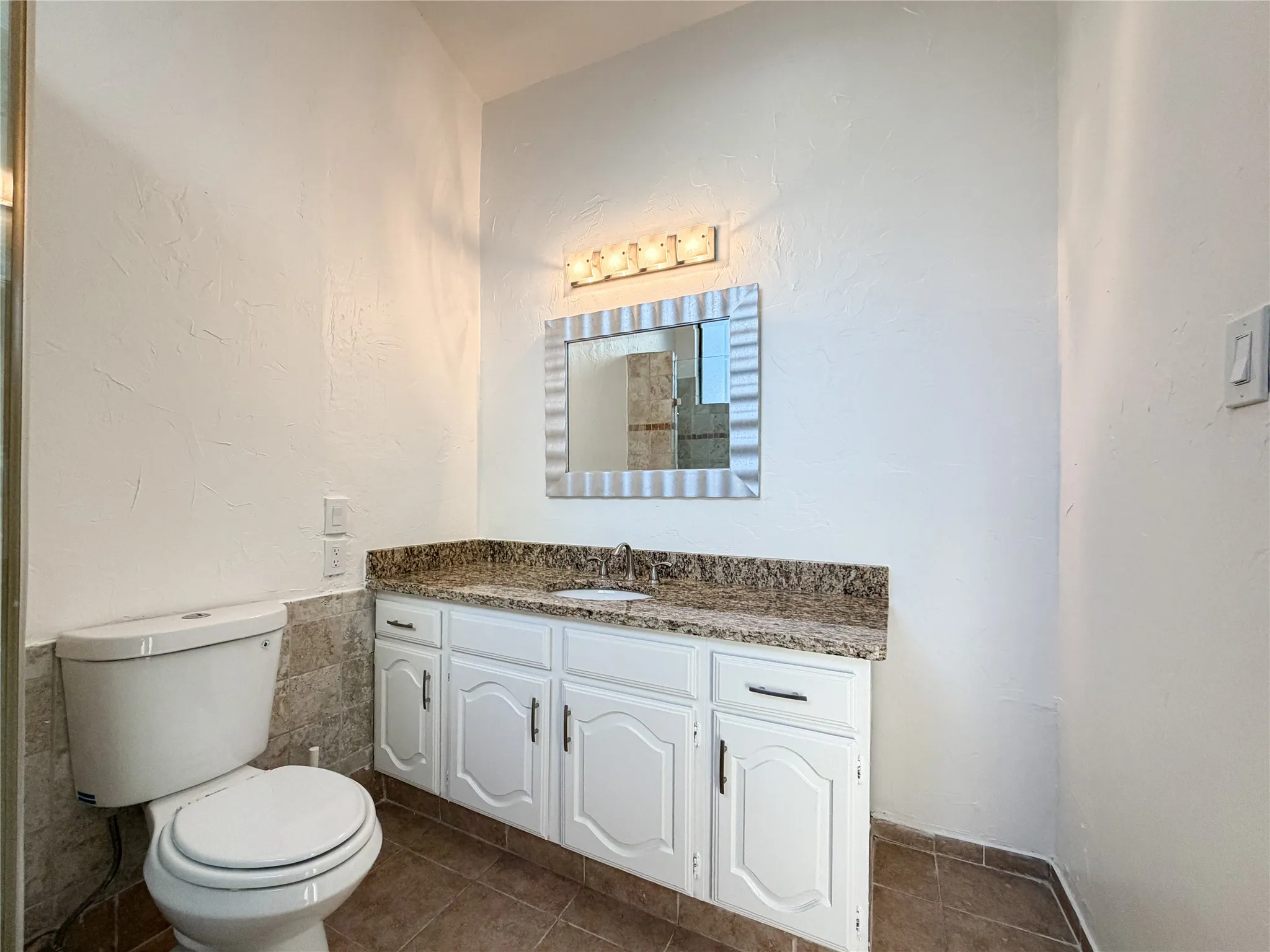 White vanity with granite countertop, undermount sink, and chrome faucet