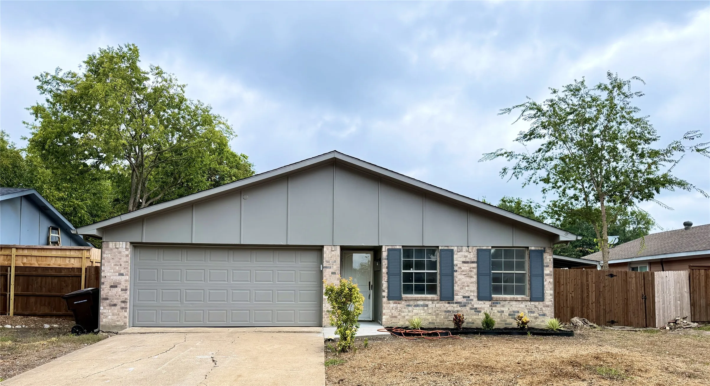 Brick and siding exterior with a pitched roof, attached garage, and front landscaping