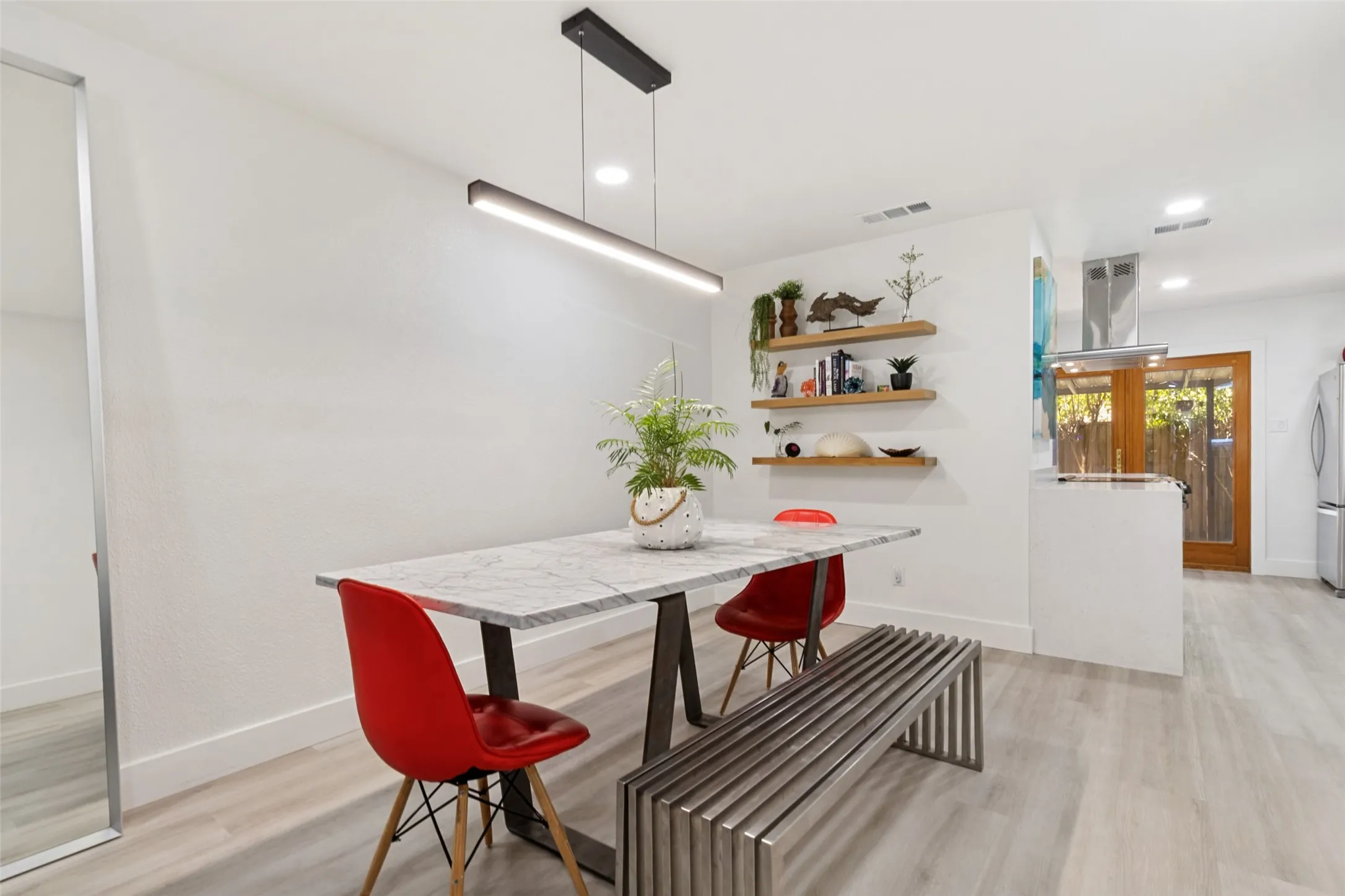 Light wood-finish flooring, white walls, and a linear pendant light