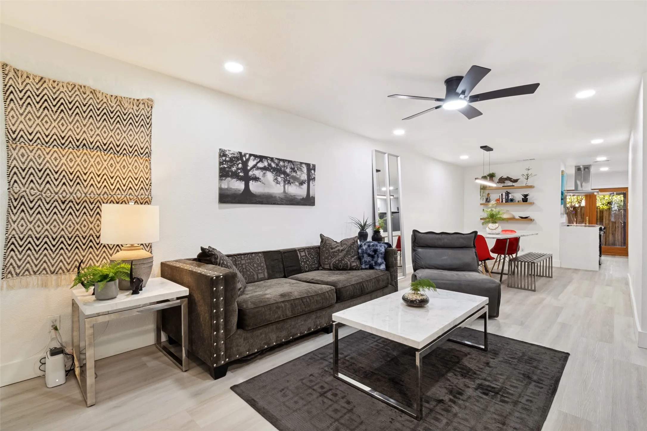 Recessed lighting, light wood-finish flooring, and a modern ceiling fan in a bright open-concept space