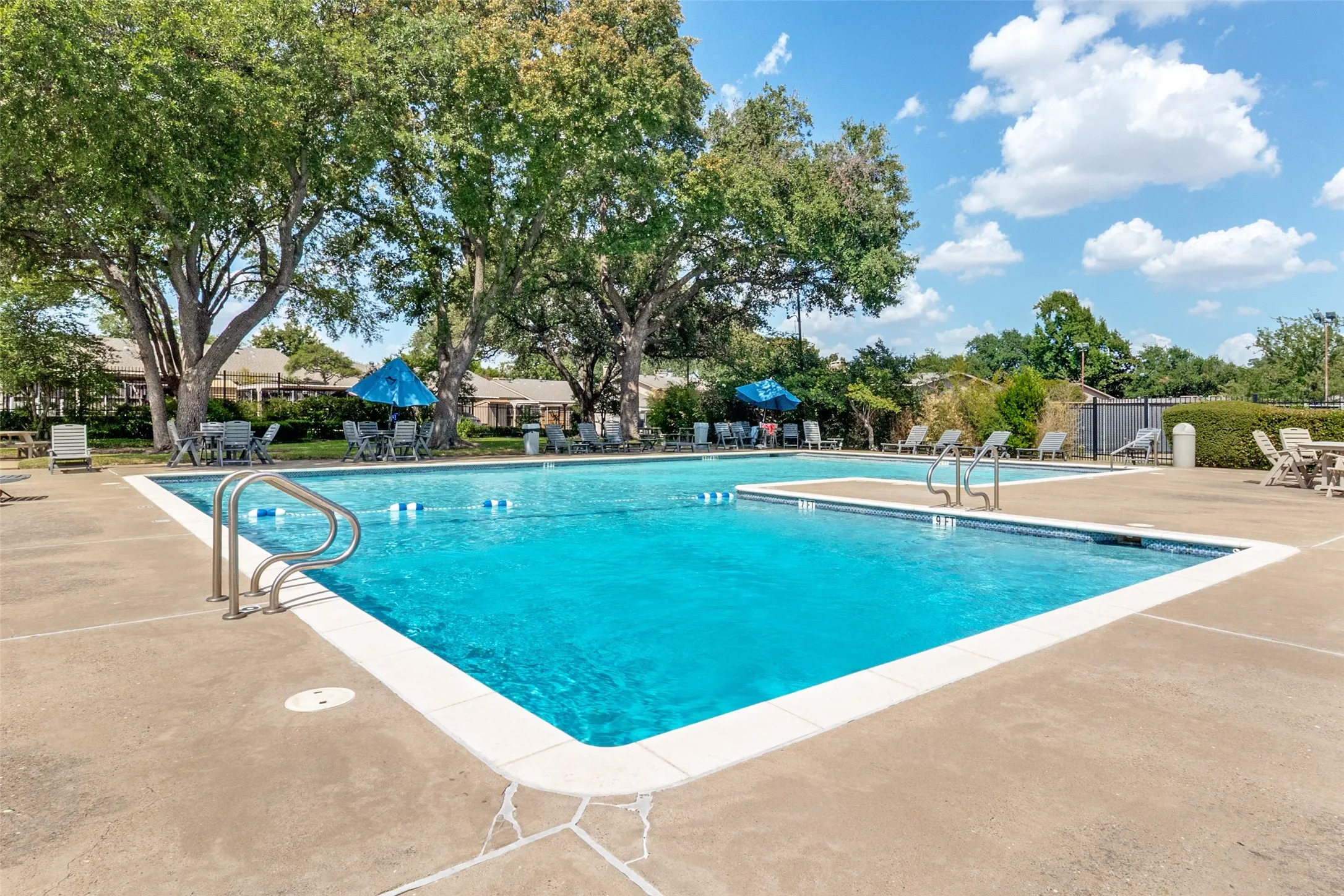 Community pool with integrated shallow area, surrounded by concrete decking