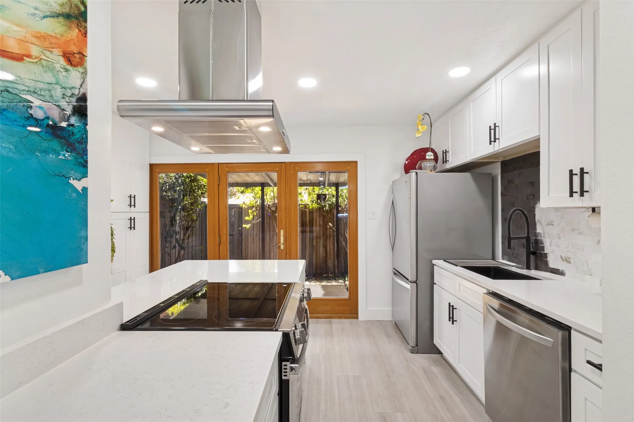 Modern kitchen featuring white cabinetry, light-toned countertops, stainless steel appliances, and a built-in cooktop