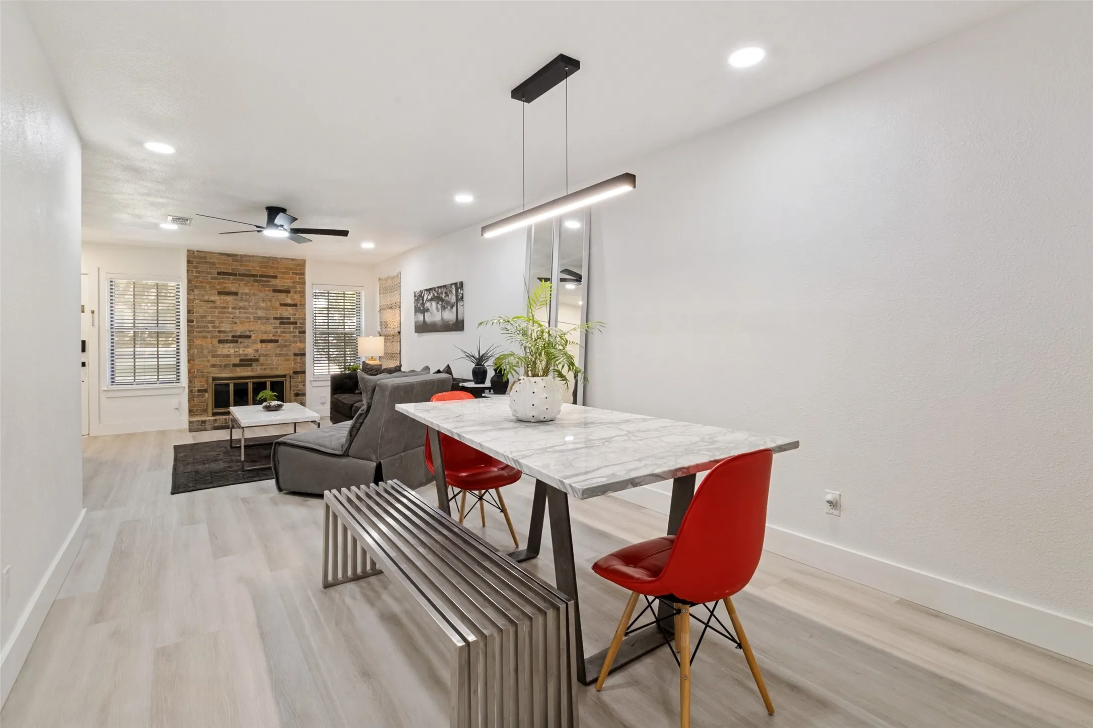 Dining area with a linear pendant light, wood-finish flooring, and recessed ceiling lights
