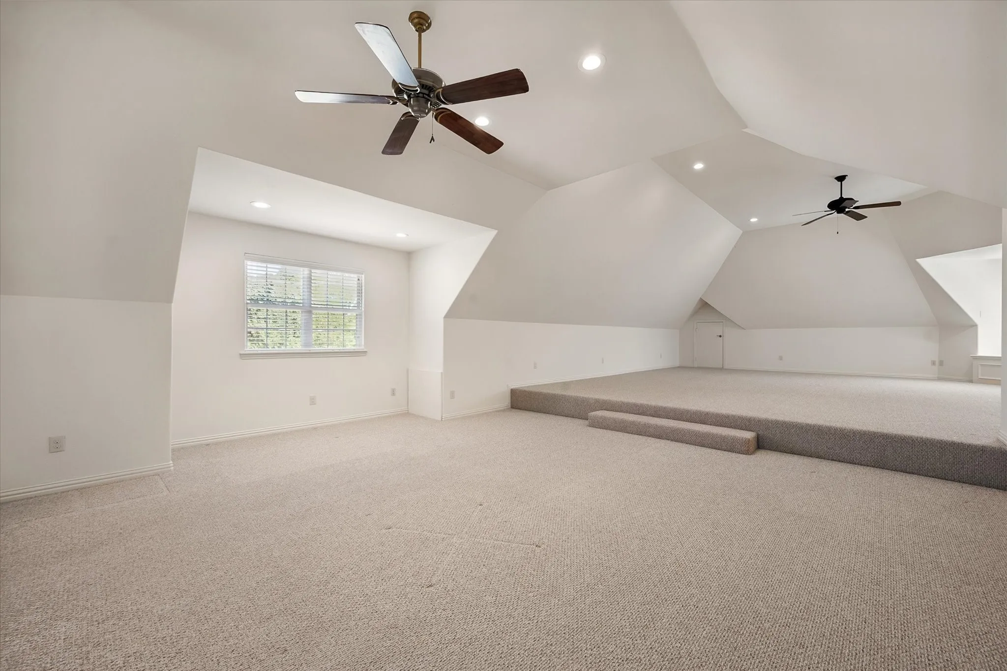 Above the garage with a separate entrance see the expansive carpeted room featuring vaulted ceilings, recessed lighting, and dual ceiling fans