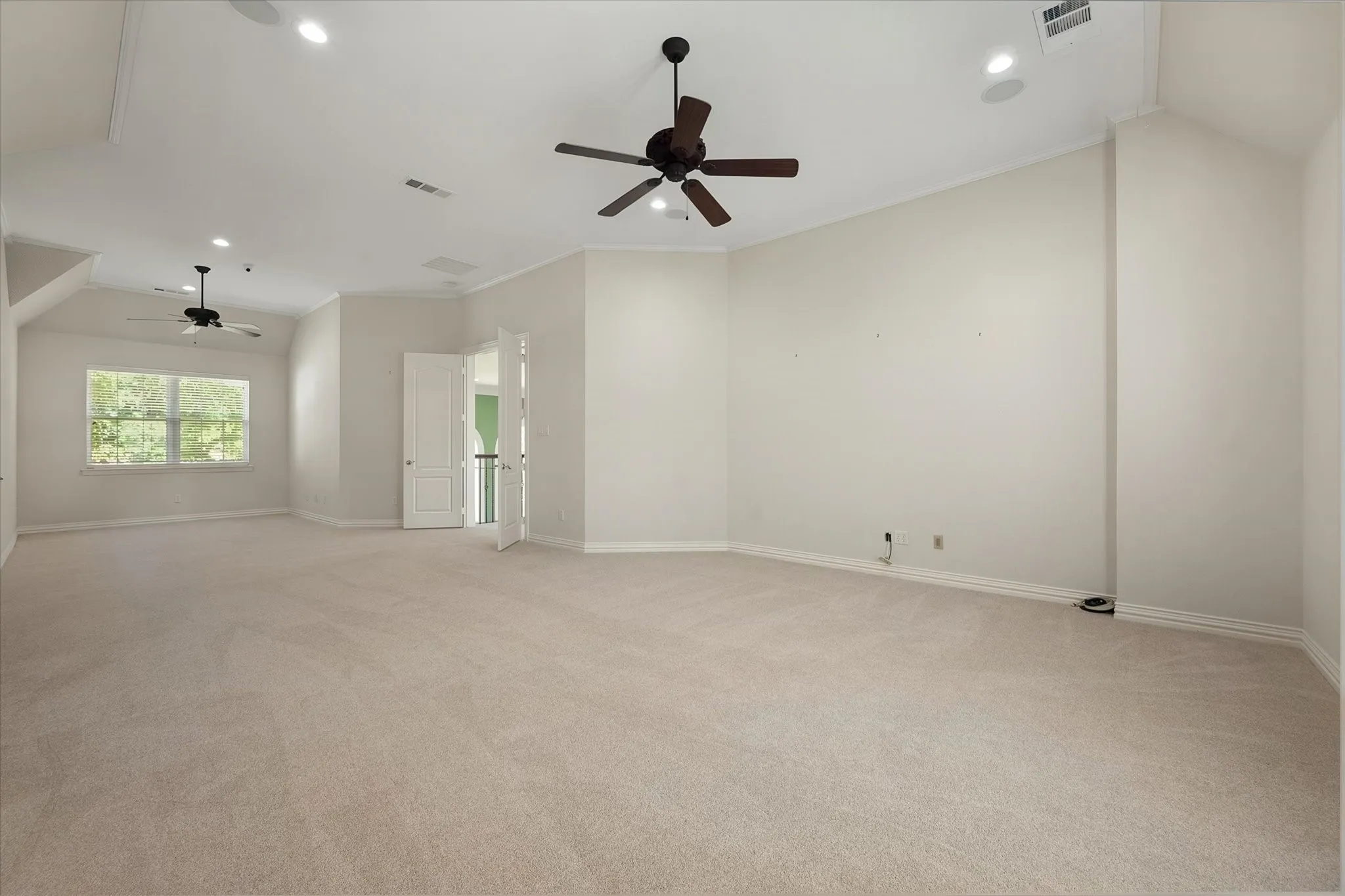 Expansive carpeted room featuring vaulted ceilings, recessed lighting, and dual ceiling fans