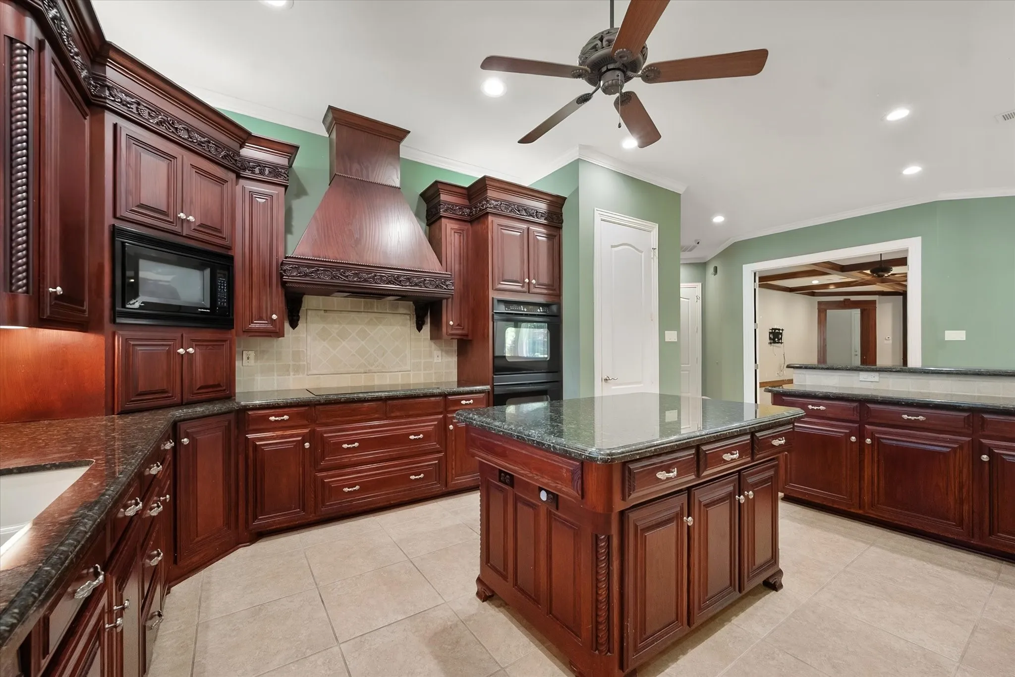Cherry wood cabinetry, stone countertops, integrated appliances, tile flooring, and a functional, exquisite central island