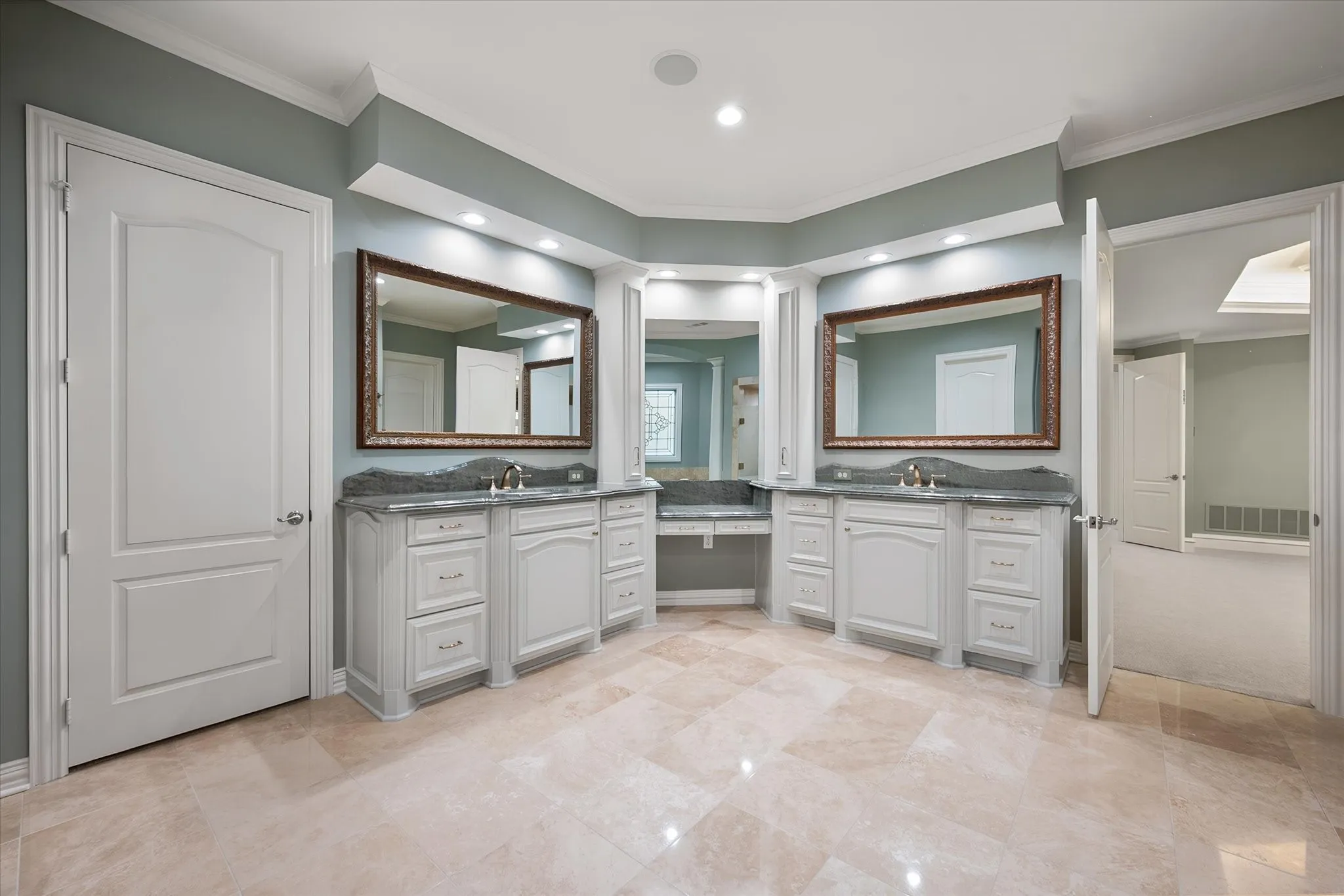 Dual vanity with undermount sinks, stone countertops, and integrated lighting with two walk in closets featuring ample storage