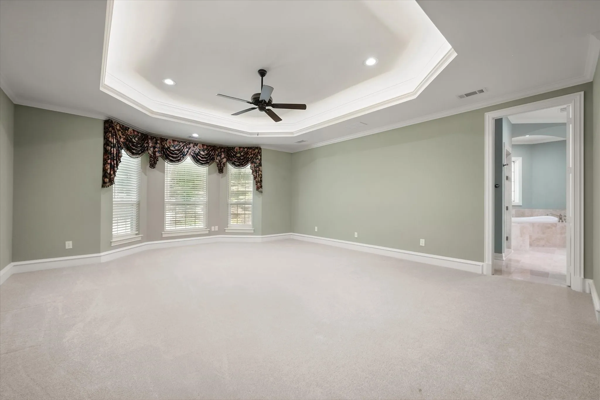 Oversized with room for extra sitting area, tray ceiling with recessed lighting and a ceiling fan