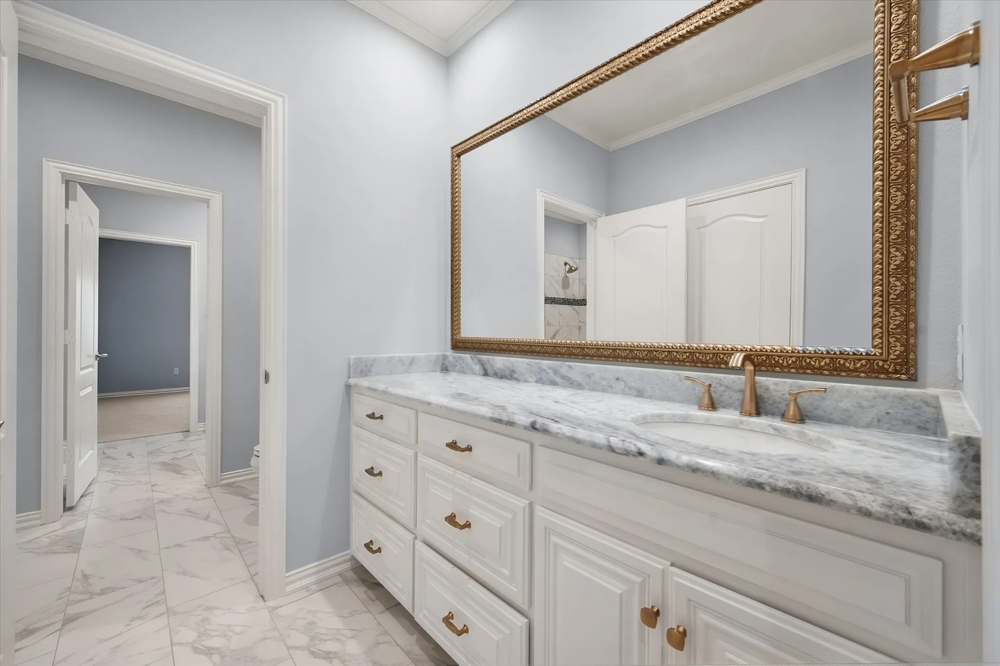 Ensuite private vanity with walk-in closet and a with exquisite countertop, under-mount sink, and a large framed mirror
