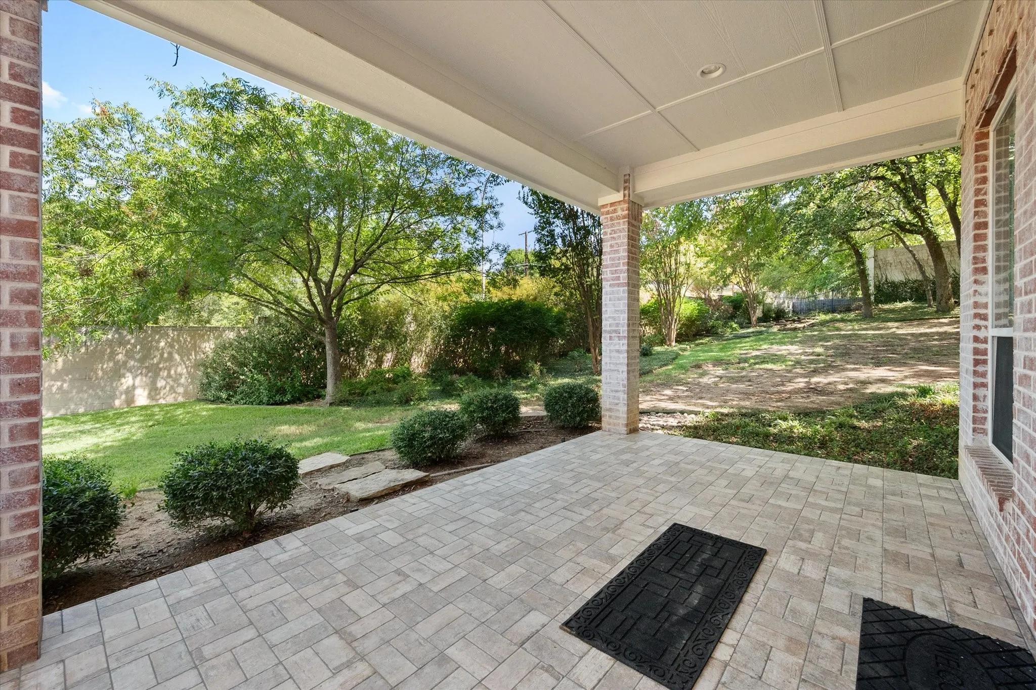 Covered patio featuring paver flooring, brick columns, and a paneled ceiling