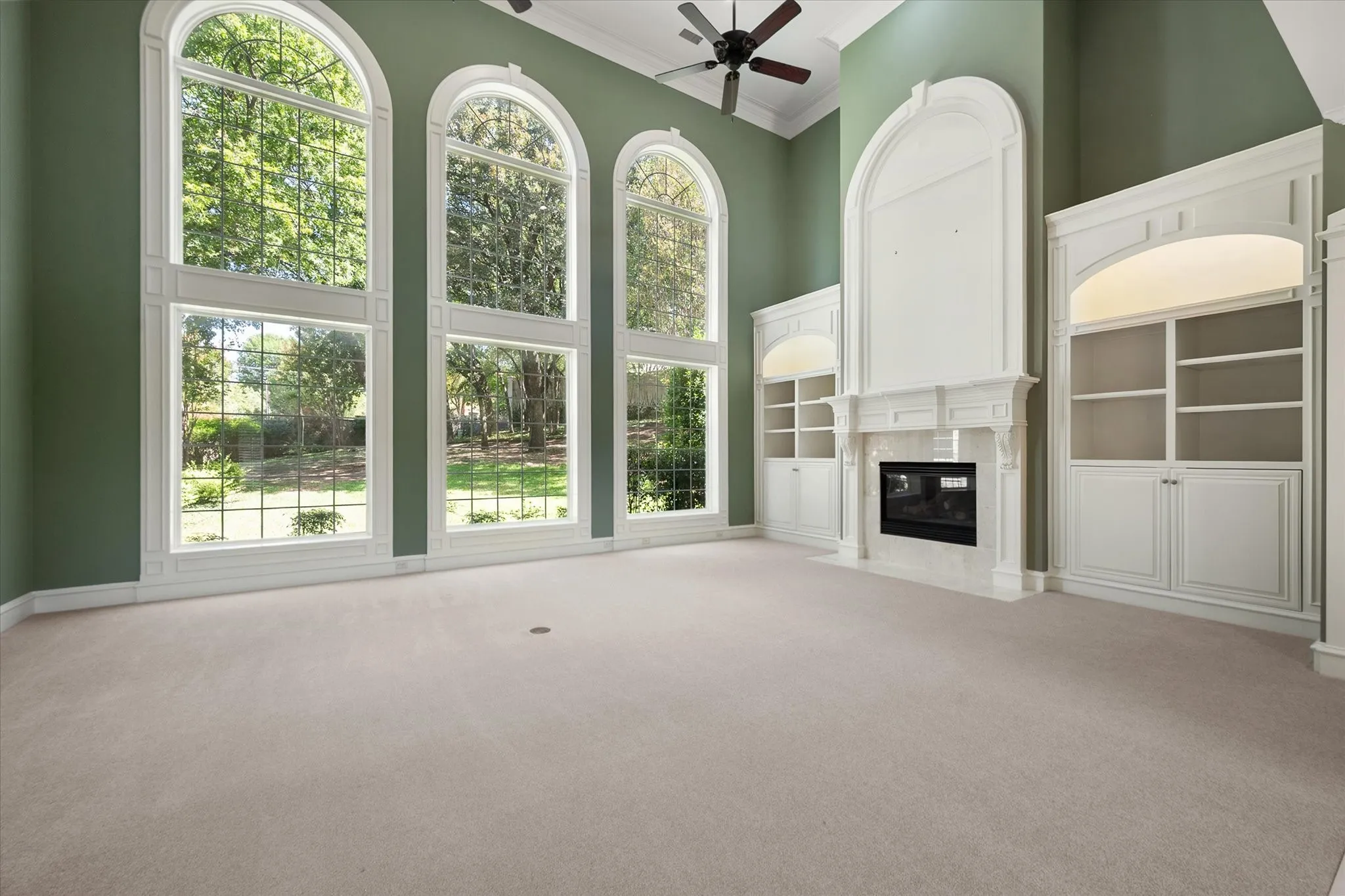 Impressive arch-top windows, high ceilings, built-in cabinetry, an integrated fireplace, and ceiling fans open to the upstairs walkway