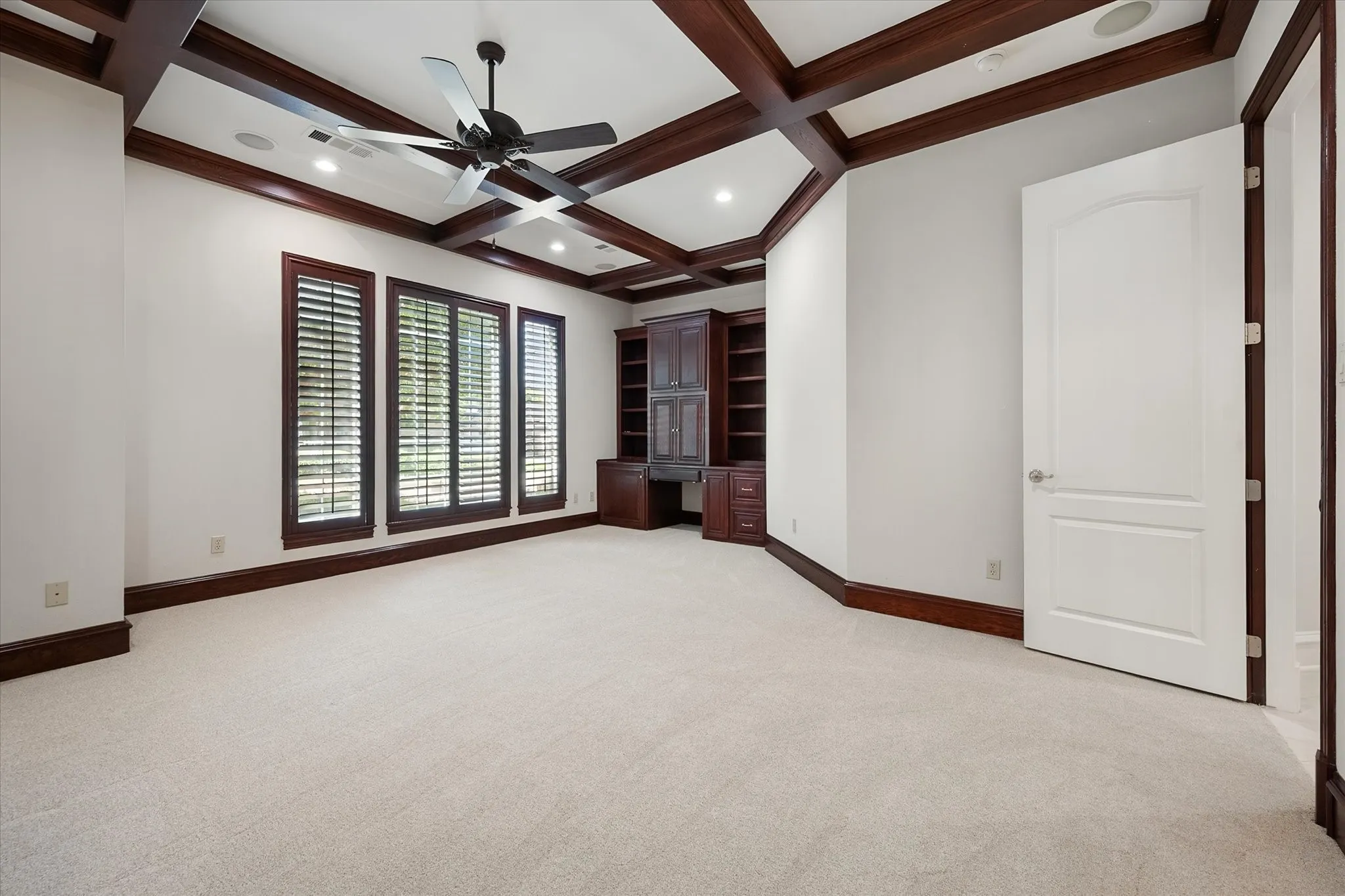 Guest Suite or Large Home office or Library with full ensuite bath, built-in cabinetry with desk, multiple windows with plantation shutters, ceiling fan, and a view of the peaceful back yard