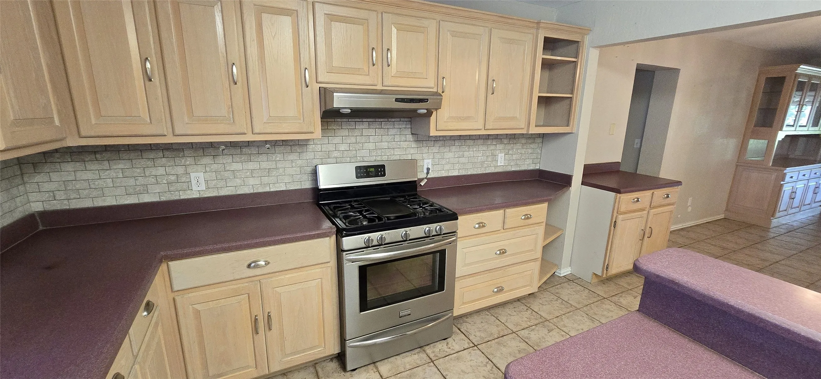 Kitchen featuring light wood-finish cabinetry, purple countertops, subway tile backsplash, stainless steel range with hood, and tile flooring