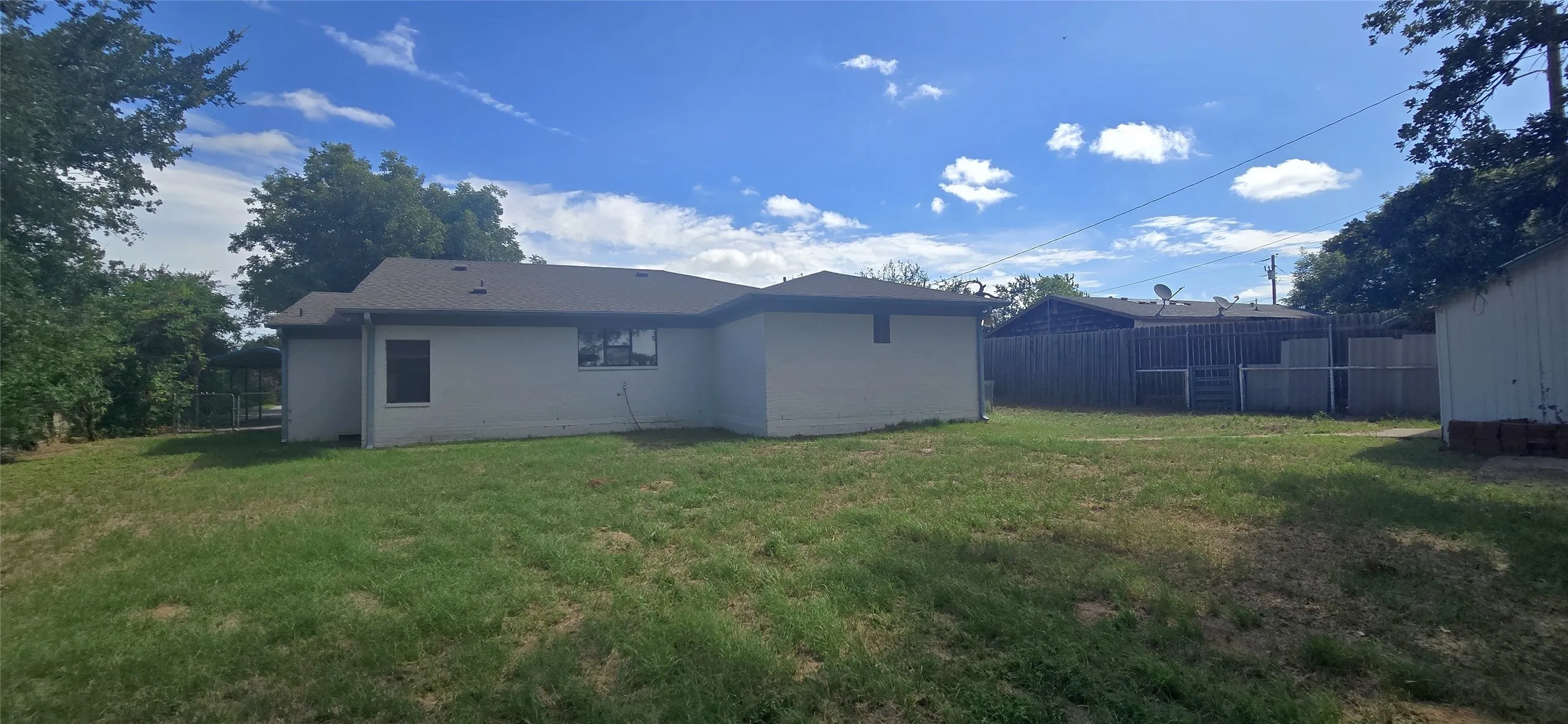 Expansive rear yard featuring a detached storage shed, stucco exterior, and multi-panel windows