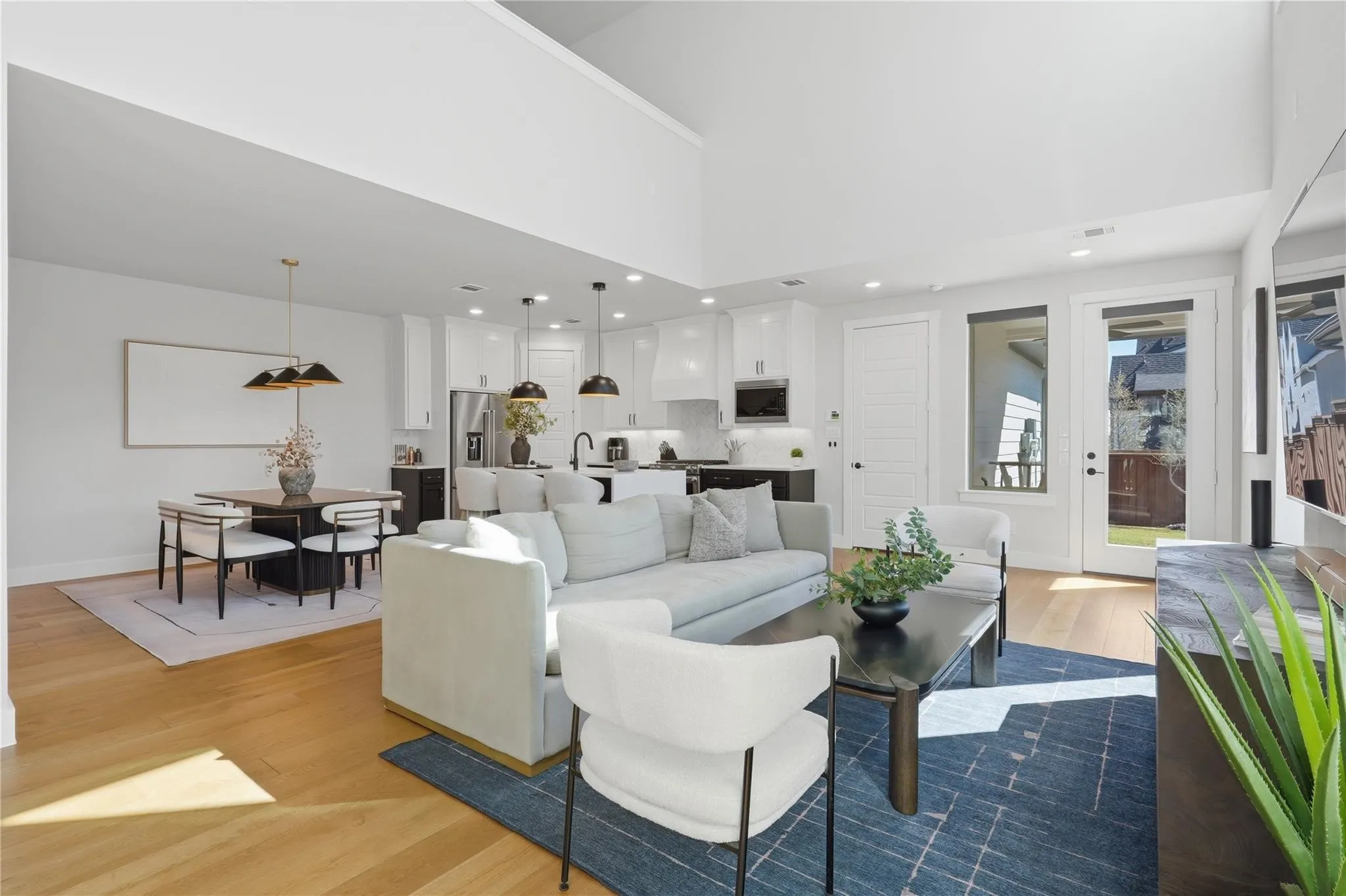 High ceilings and wood-finish flooring complement the white shaker cabinetry and integrated stainless steel appliances