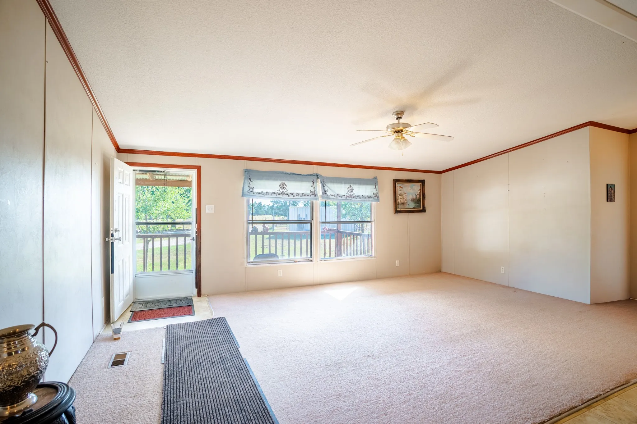 Carpet flooring throughout, multiple windows, ceiling fan with light fixture, and crown molding