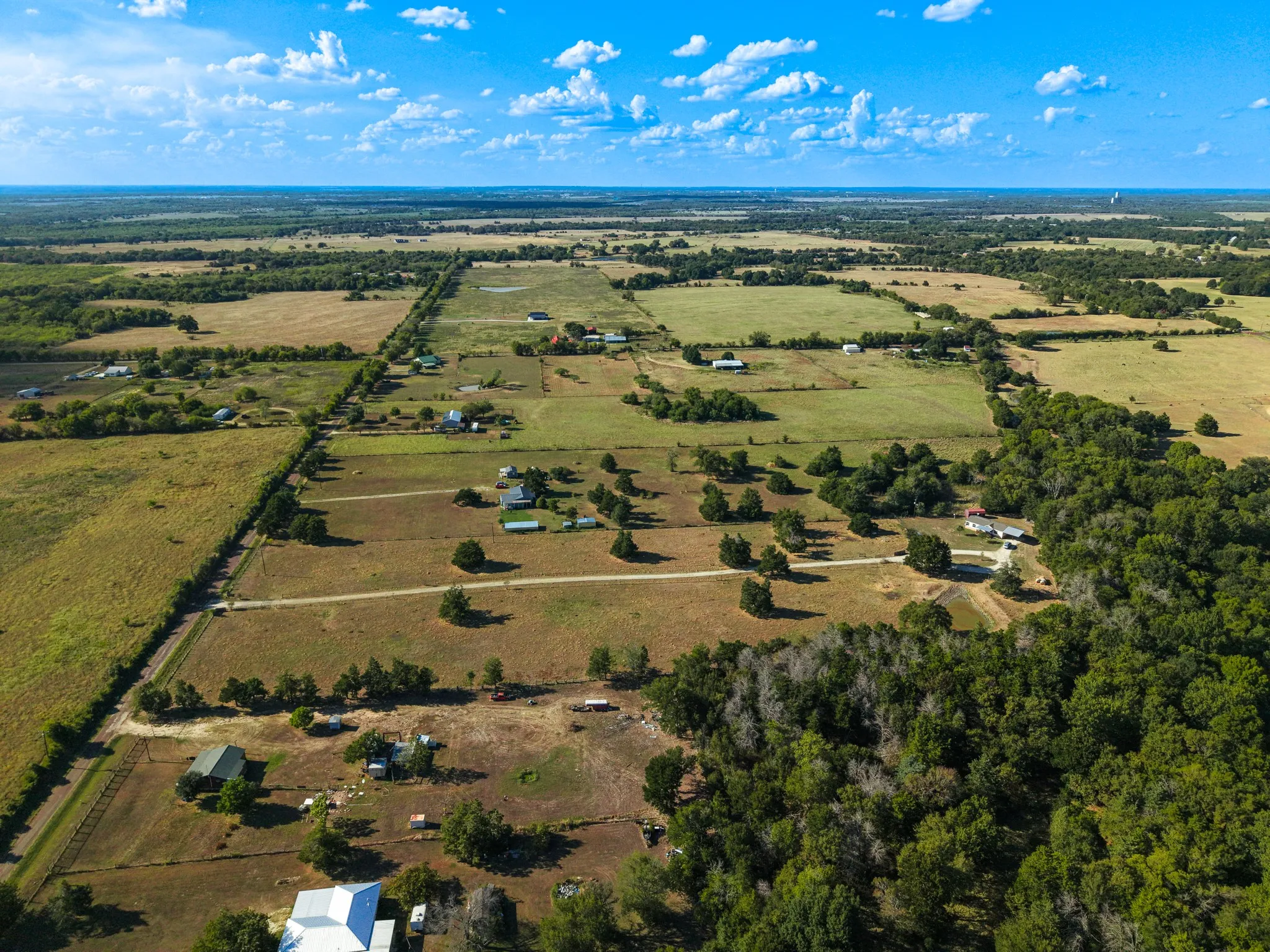 Expansive rural landscape featuring scattered residences, open fields, and mature tree lines