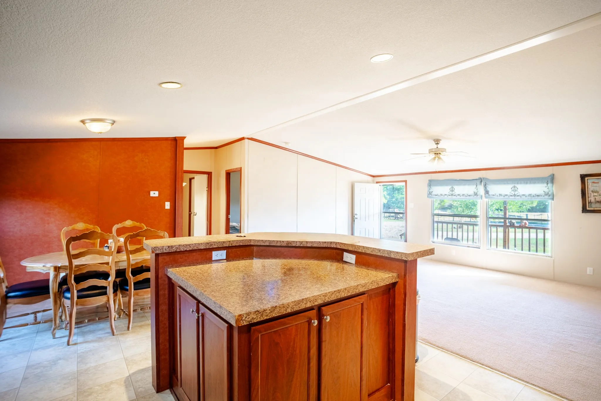 Kitchen island with granite-finish countertop, wood-finish cabinetry, and built-in electrical outlets
