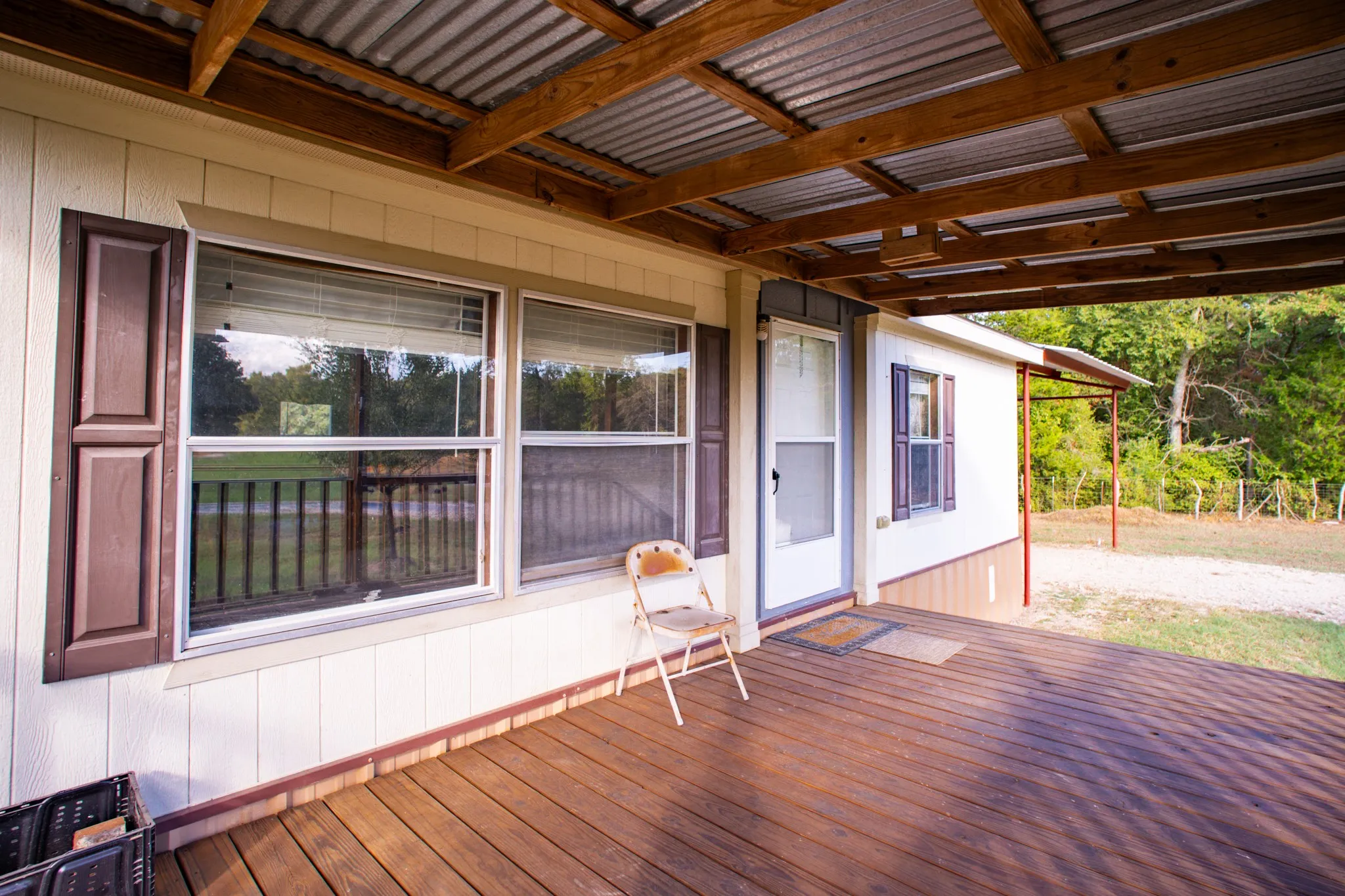 Expansive wood-finish deck with a corrugated metal roof supported by exposed wood beams