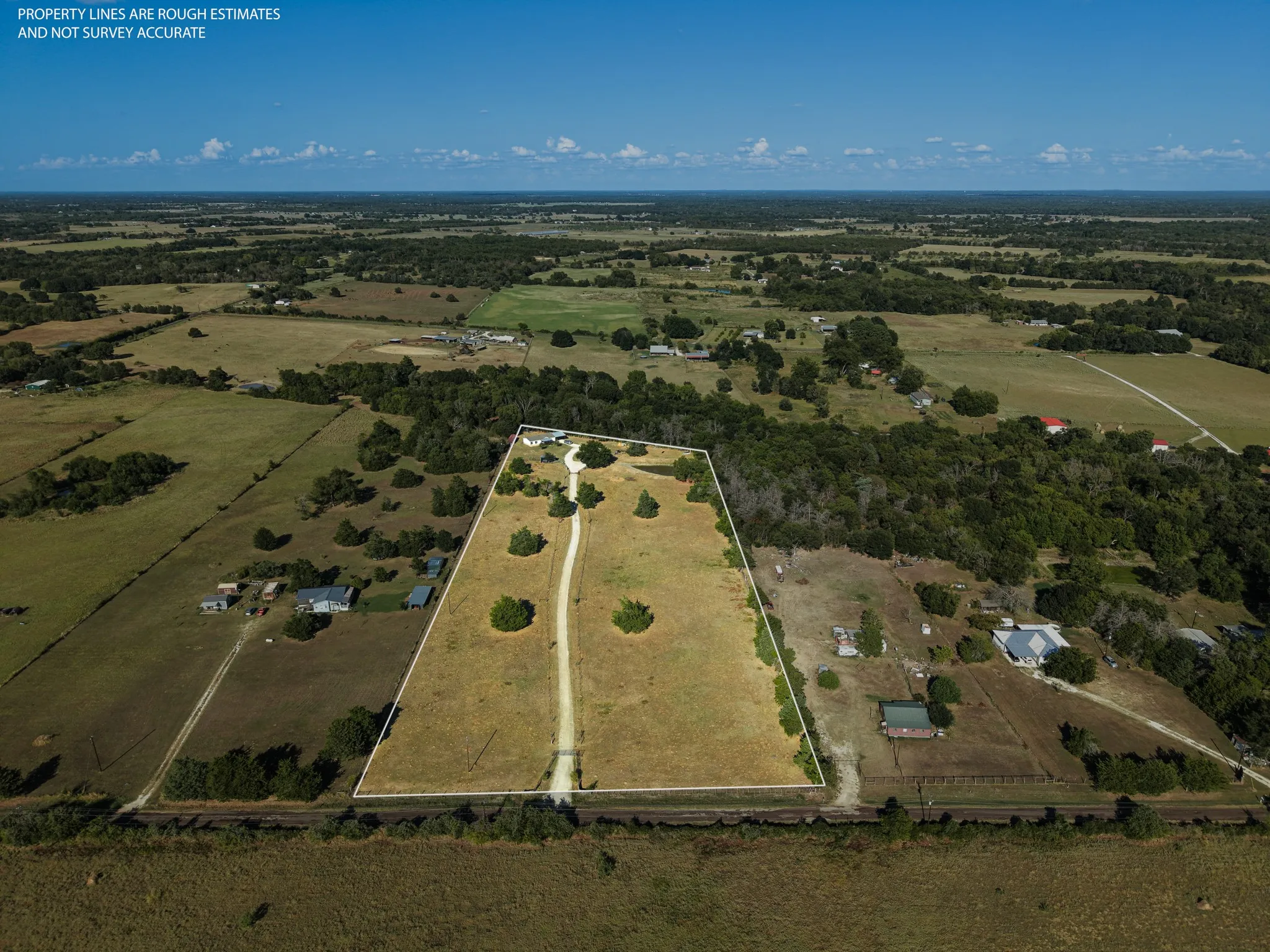 Expansive rural property featuring a primary residence, multiple outbuildings, and a private driveway