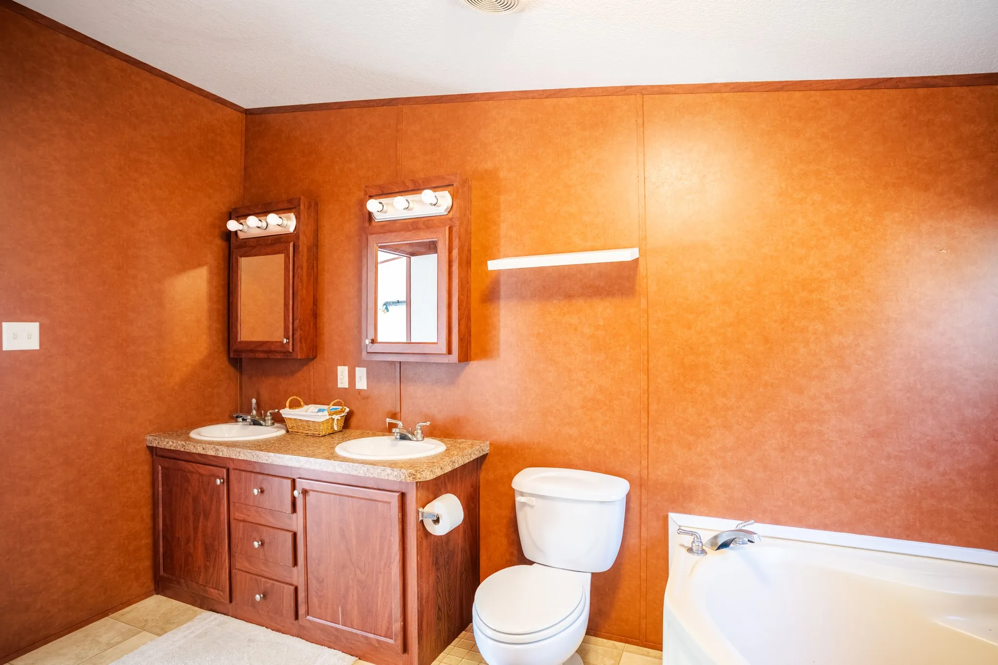 Dual vanity with wood-finish cabinetry, integrated sinks, and individual mirrored medicine cabinets