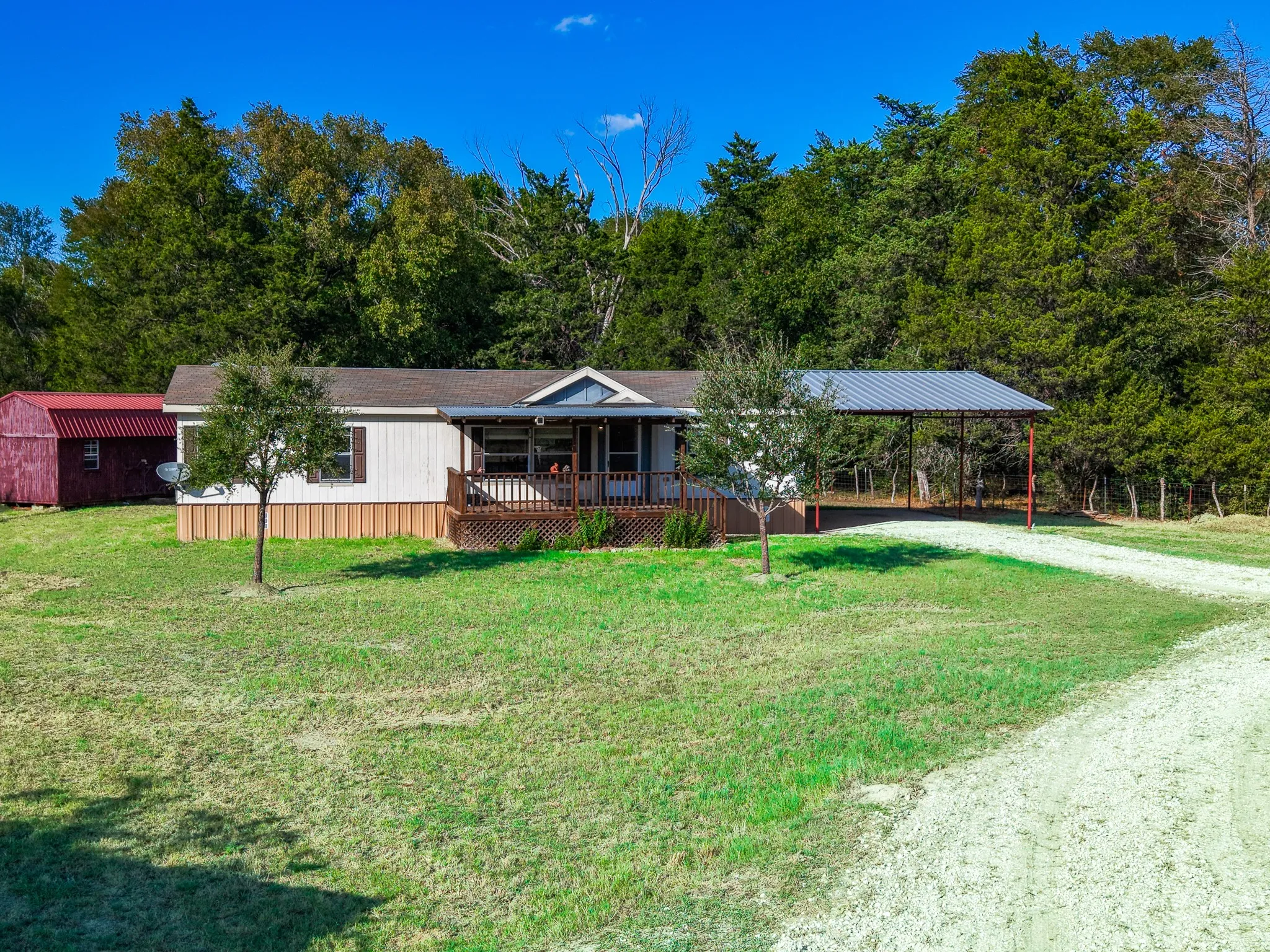 Single-story residence with a covered front porch, an attached carport, and a separate red storage shed