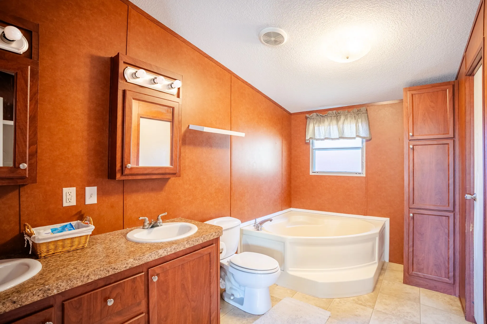 Dual vanity with integrated sinks, wood-finish cabinetry, and laminate countertops