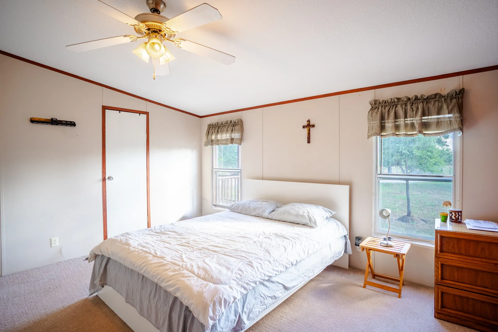Carpeted bedroom with a ceiling fan, a white door, and two windows