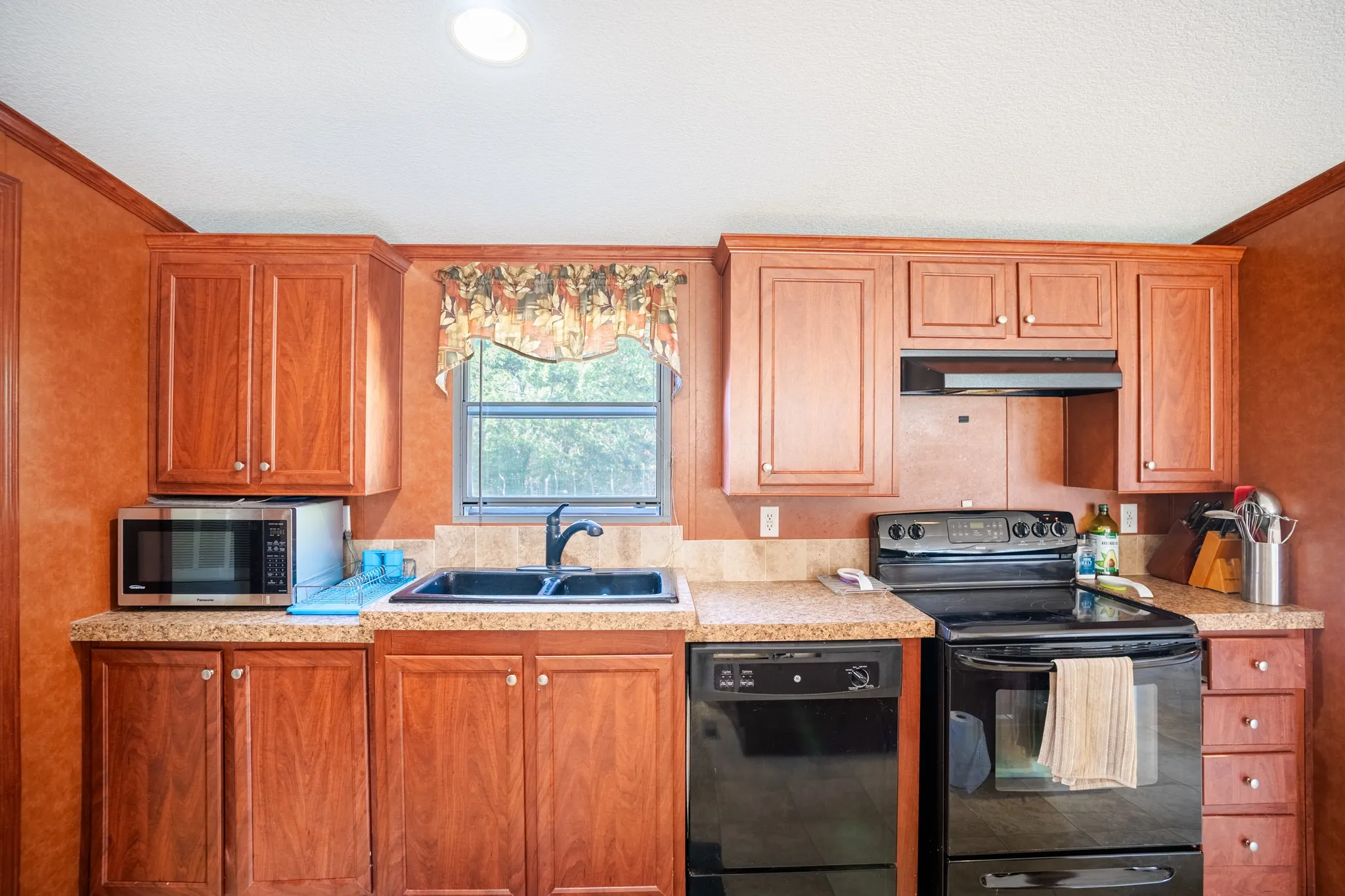 Kitchen featuring wood-finish cabinetry, speckled countertops, and a double basin sink with a gooseneck faucet