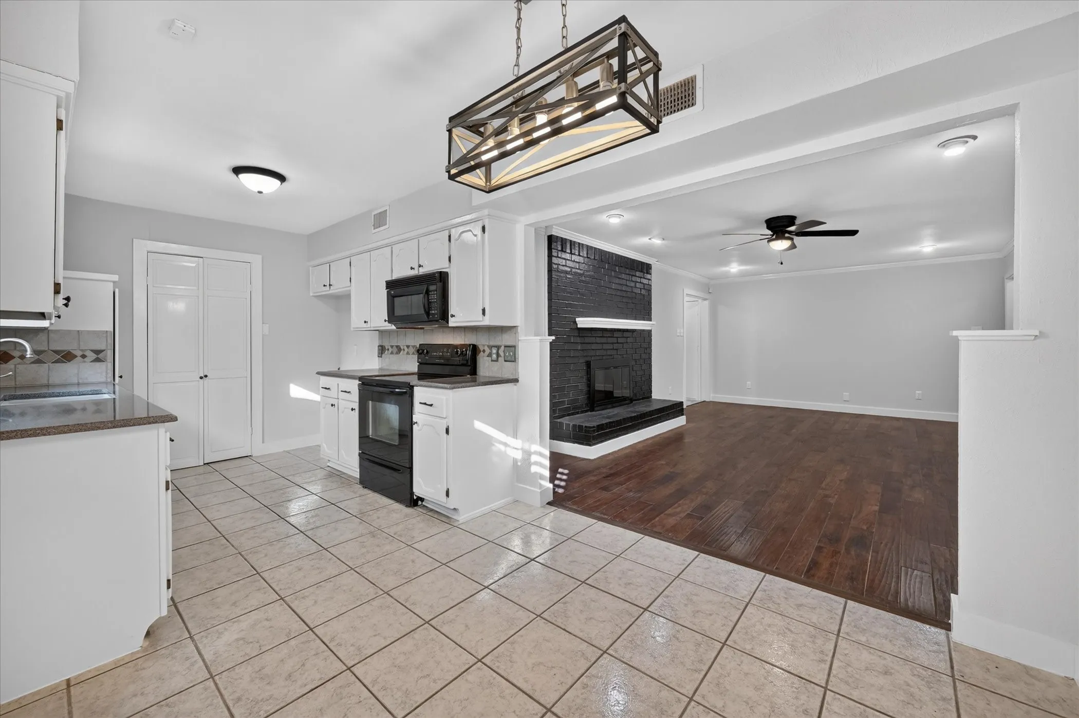 Kitchen featuring white cabinetry, tile flooring, and integrated black appliances