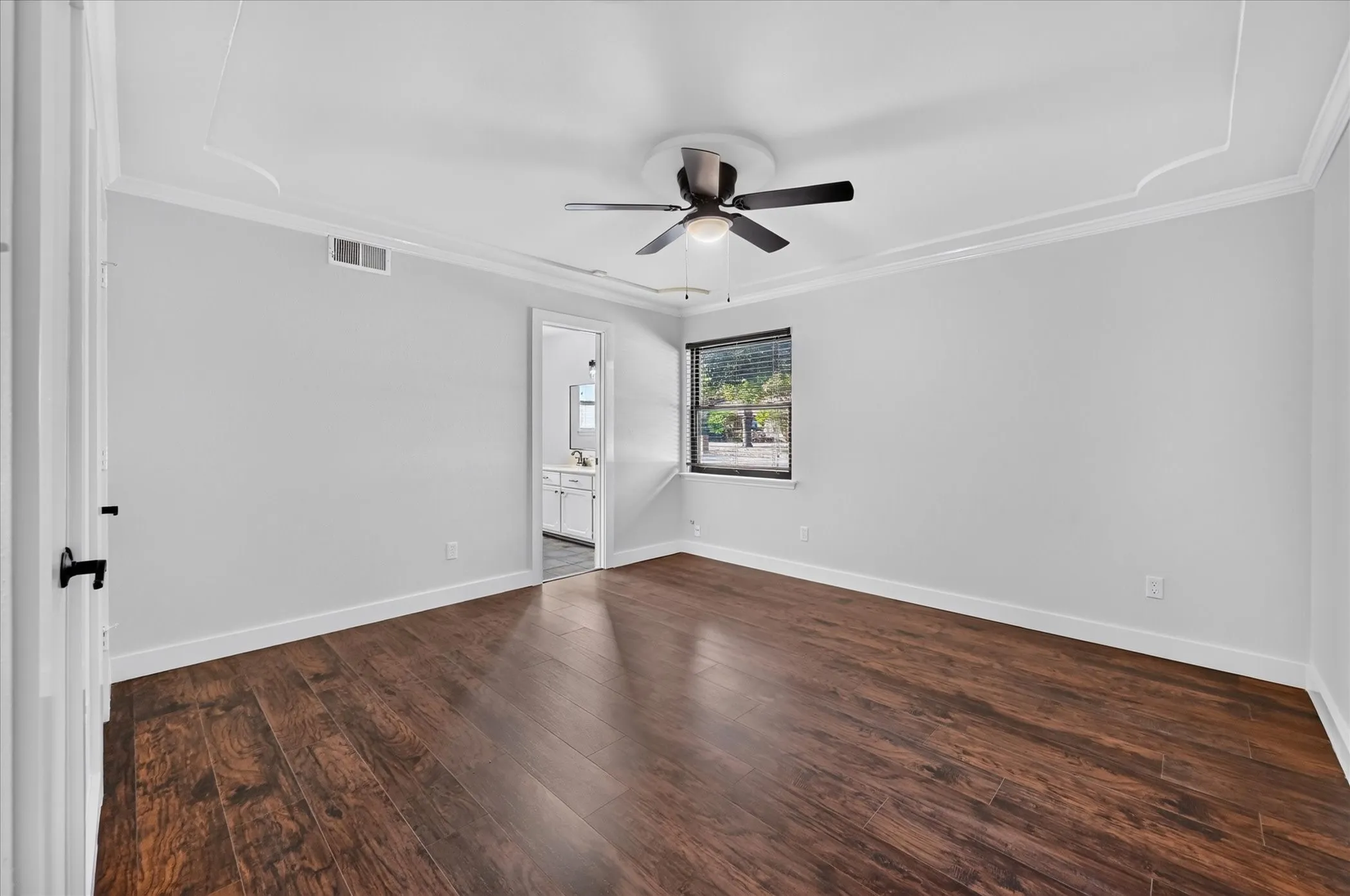 Wood-finish flooring, ceiling fan, white trim, and a window with blinds