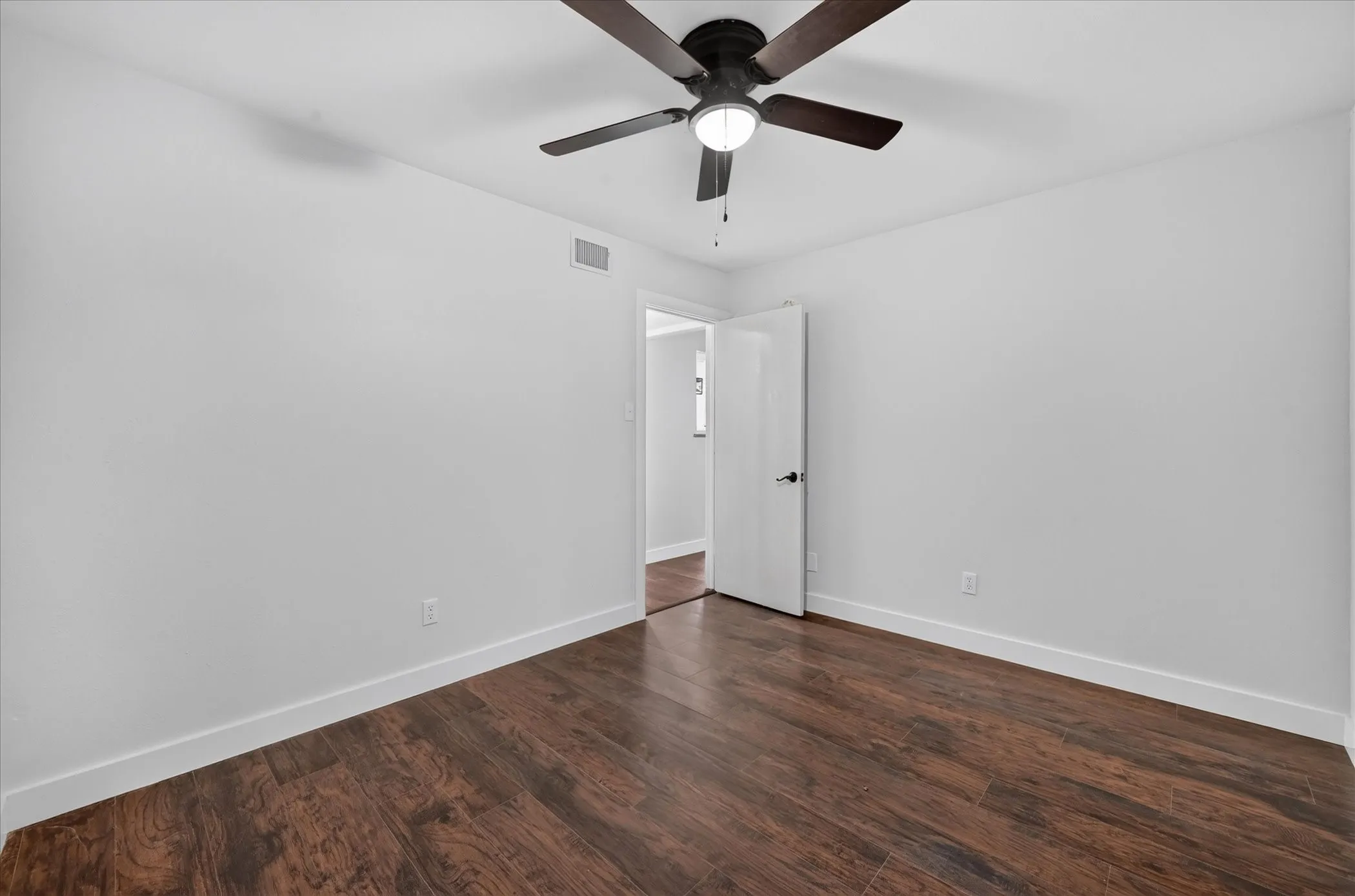 Wood-finish flooring, white walls, white trim, and a ceiling fan with integrated lighting