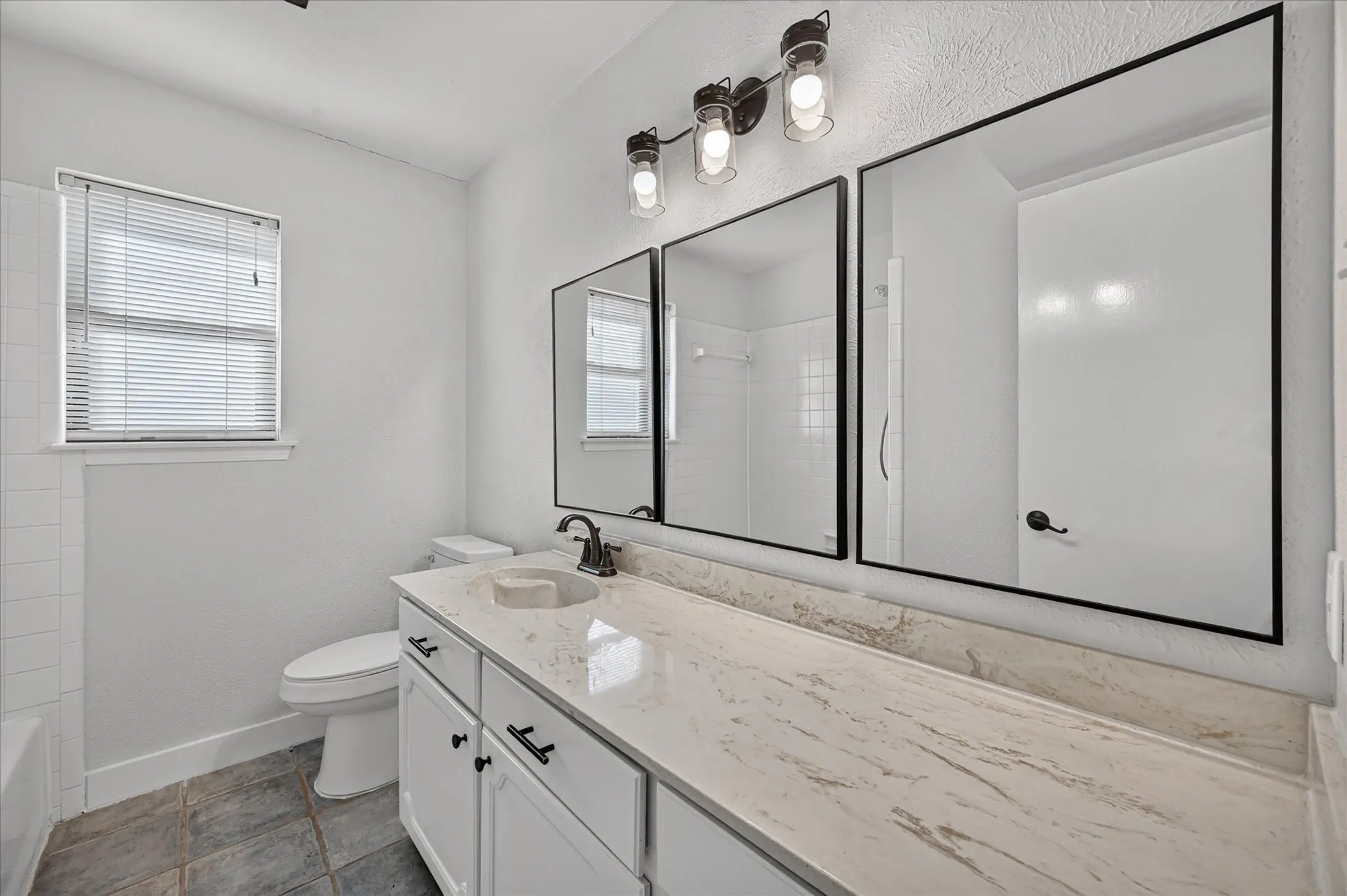 Vanity with an integrated sink, black faucet, and white cabinetry with black hardware