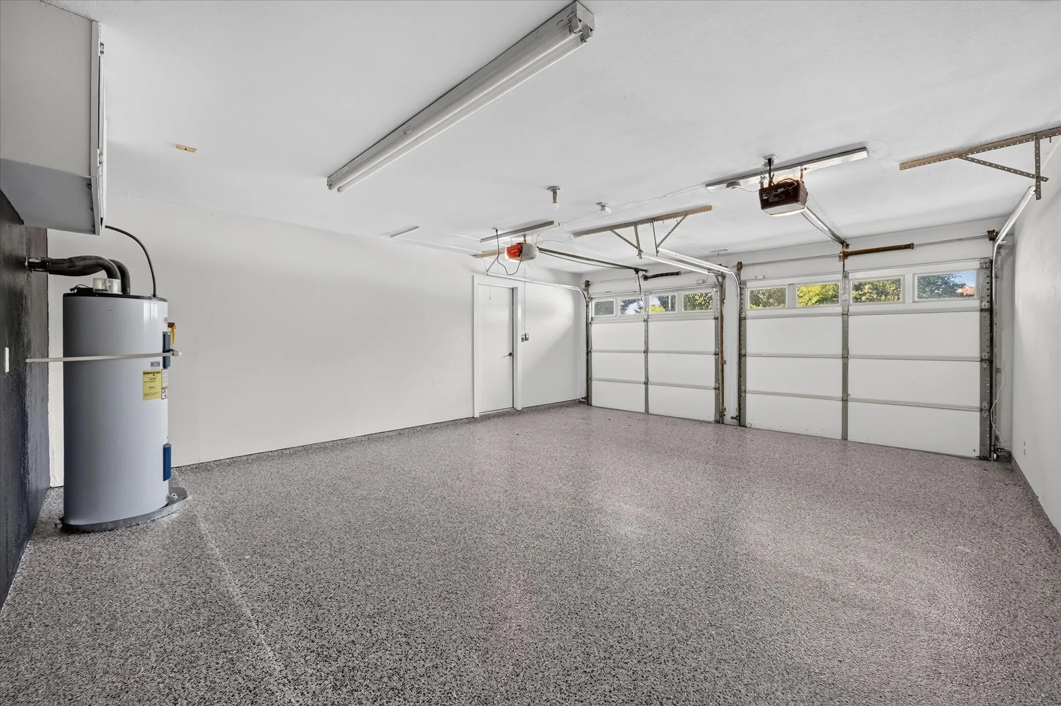 Two-car garage with speckled epoxy flooring, two overhead garage doors with window panels, and an interior access door