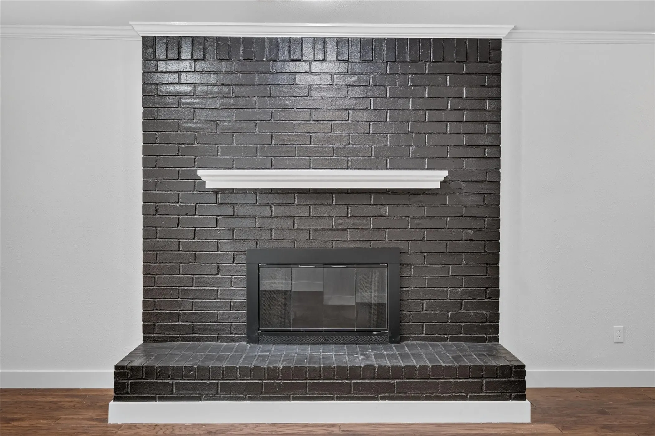 Brick fireplace with a dark finish, integrated firebox, and a white mantel