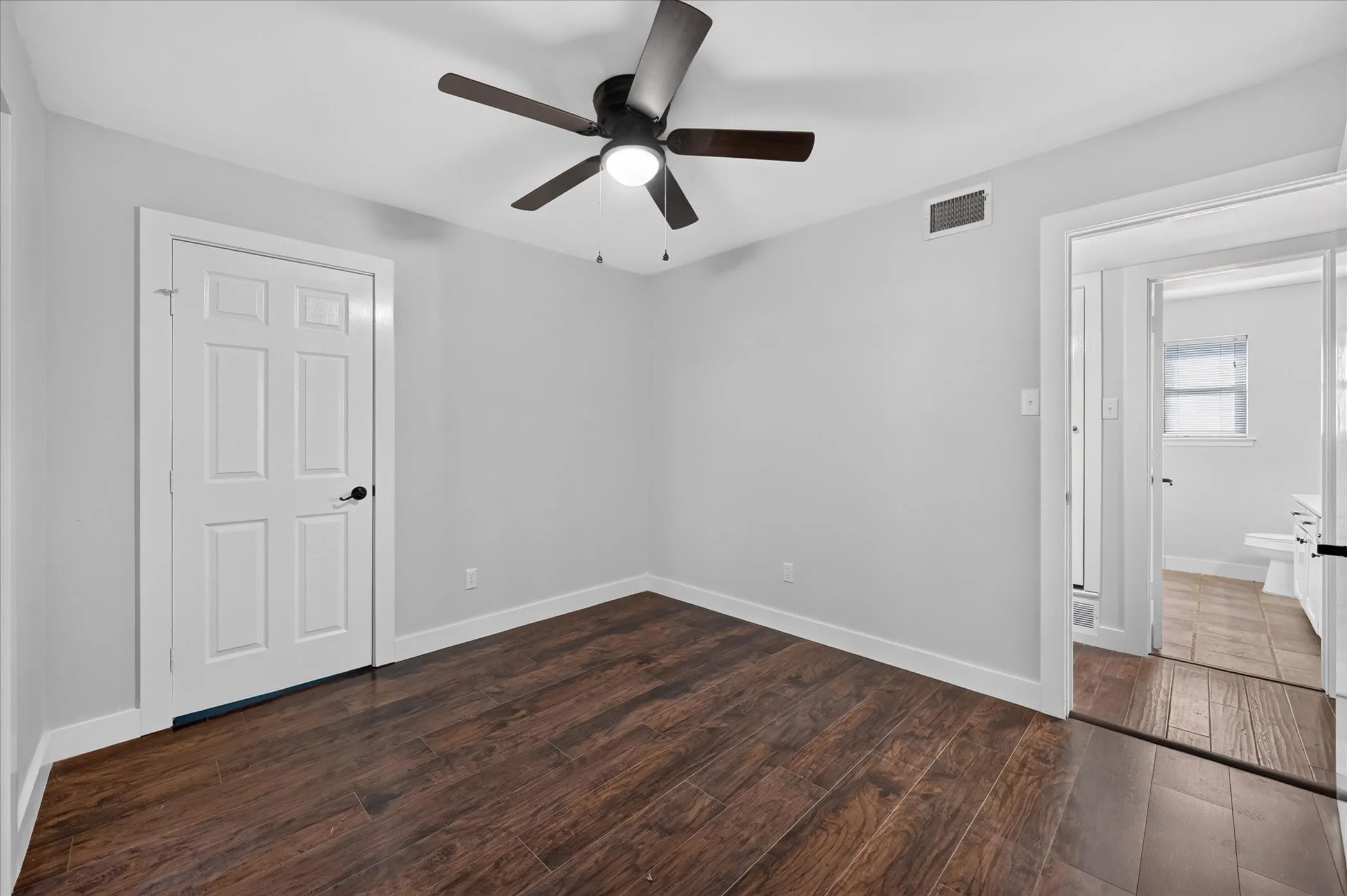 Wood-finish flooring with a ceiling fan light fixture and white paneled doors