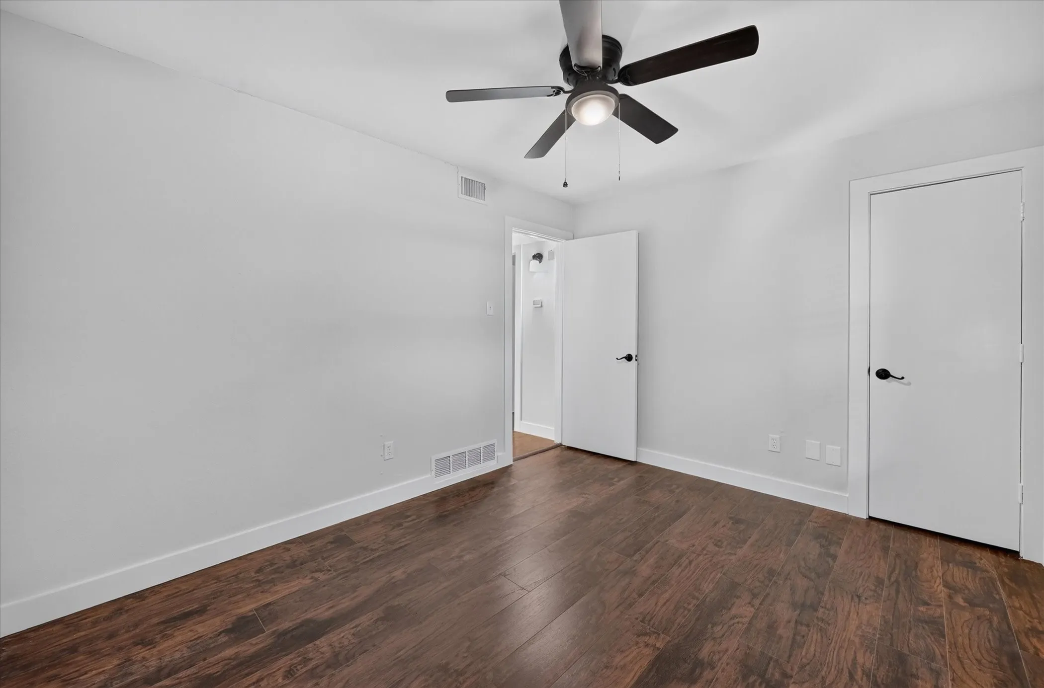 Dark wood-finish flooring with white baseboards