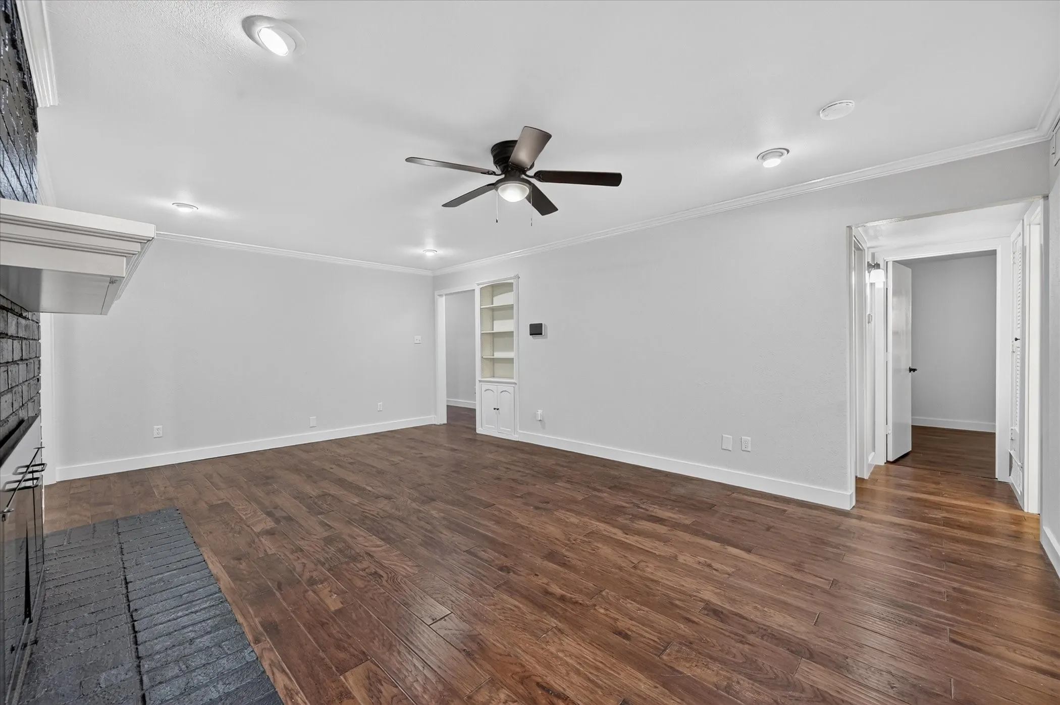 Wood-finish flooring, recessed lighting, ceiling fan, crown molding, and built-in shelving