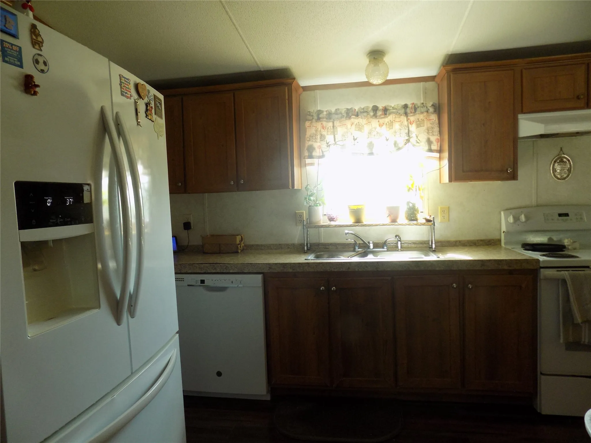 Kitchen featuring wood-finish cabinetry, a window over the dual, stainless steel sink, and a built-in dishwasher