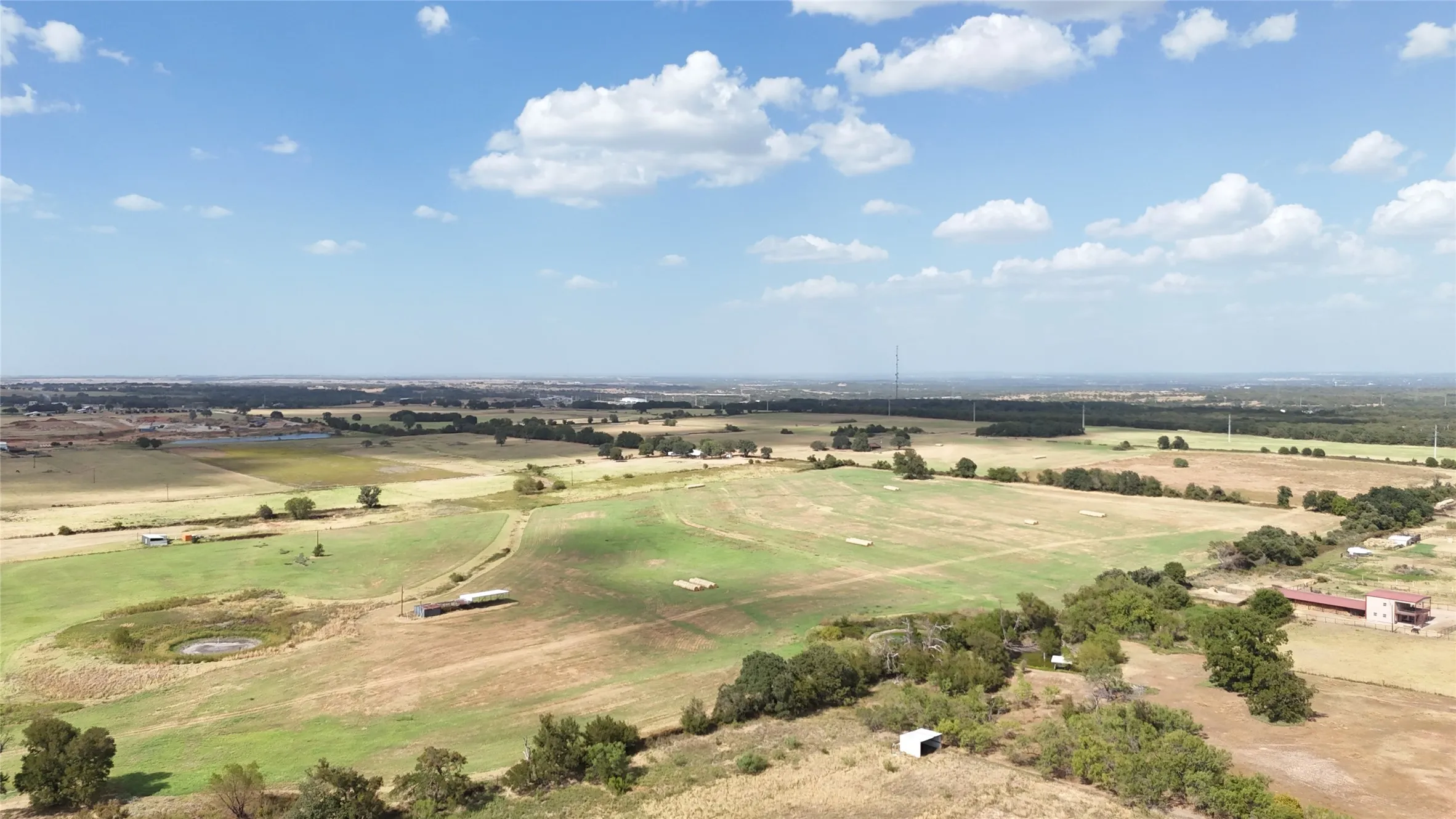 Expansive open fields with varied terrain, including areas of green grass and drier land