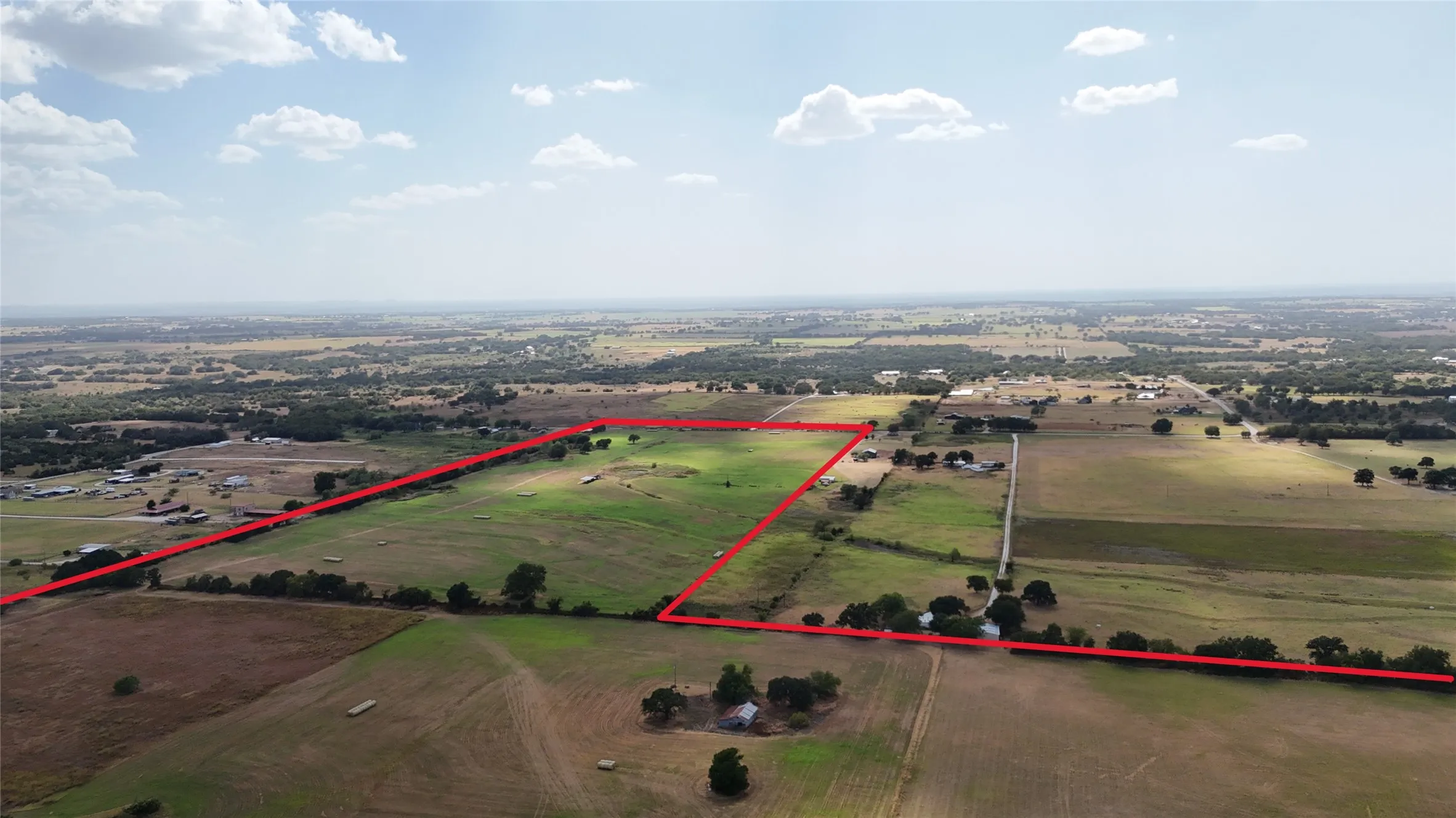Expansive land parcel featuring open fields and distant tree lines