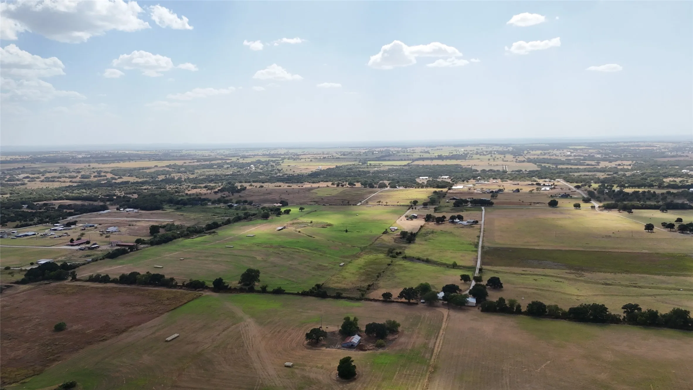 Expansive rural landscape with varied terrain, including cultivated fields and tree lines