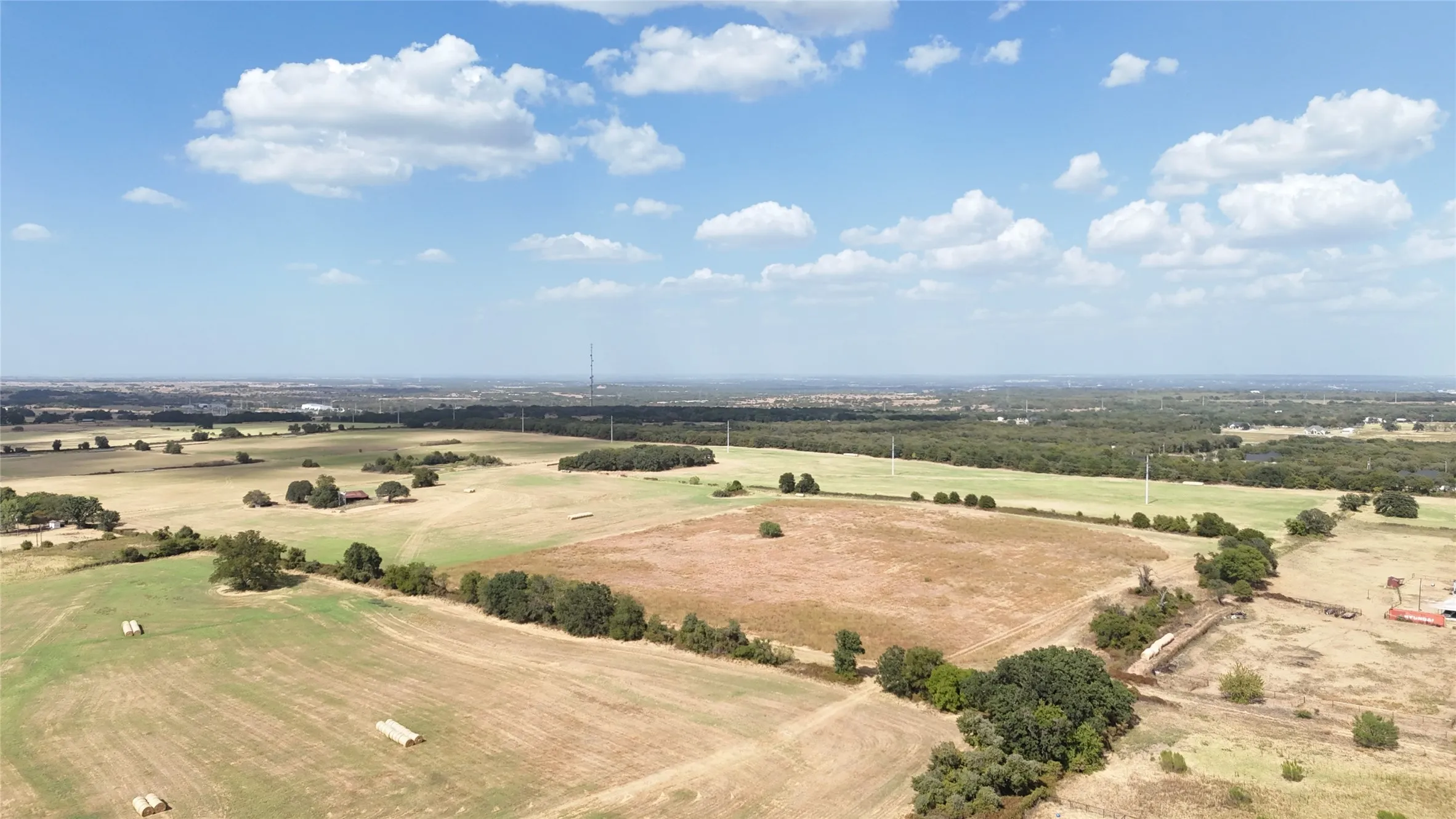 Expansive acreage featuring open fields, scattered mature trees, and a distant urban horizon