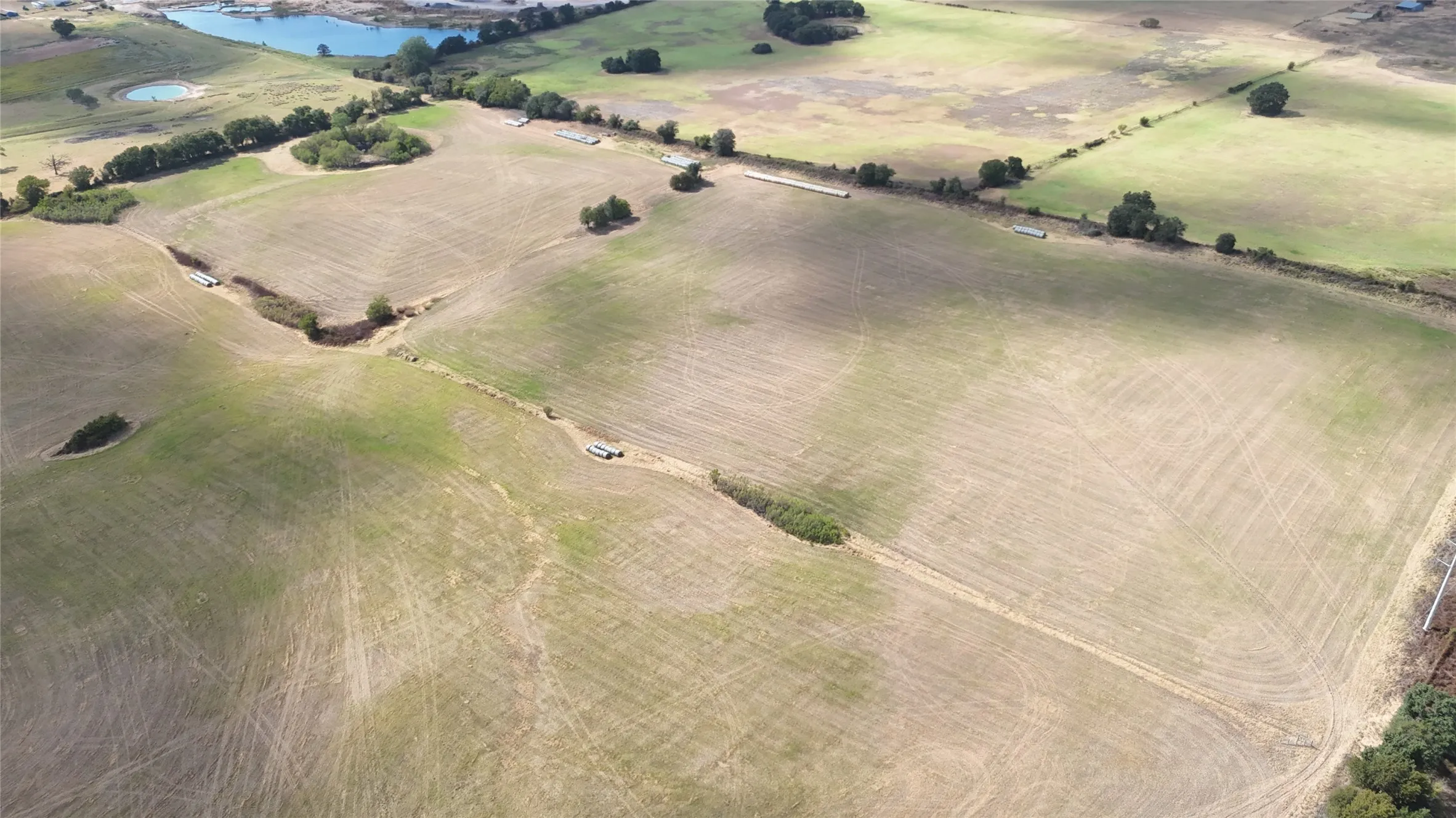 Expansive land parcel featuring varied terrain, natural water features, scattered trees, and visible agricultural patterns