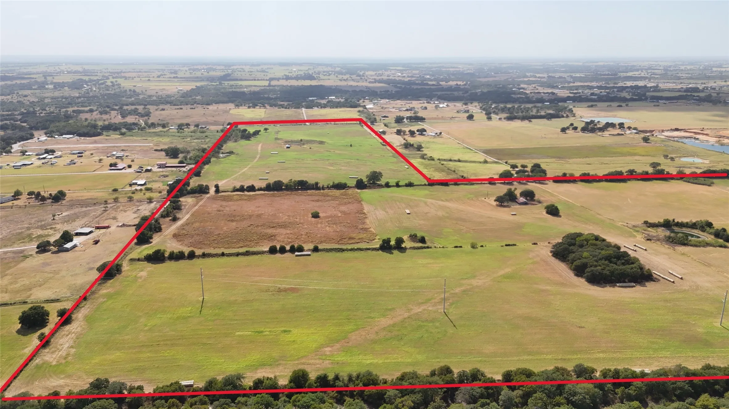 Expansive acreage featuring open fields, scattered mature trees, and a natural water feature
