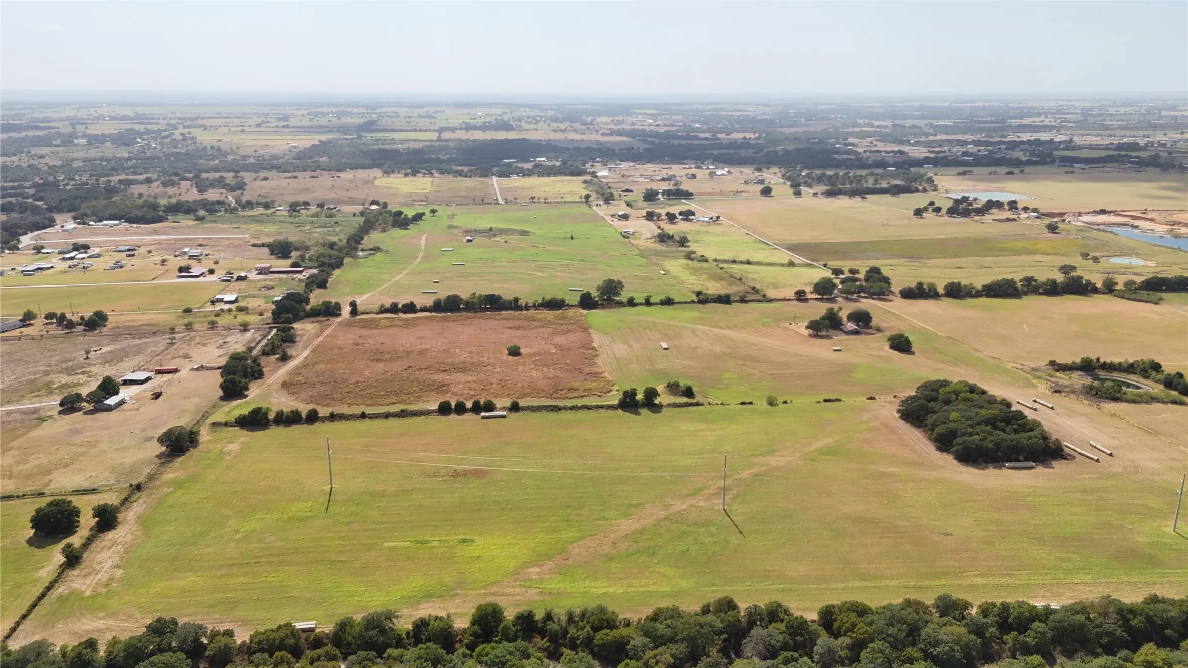 Expansive land featuring a mix of open fields and scattered treelines