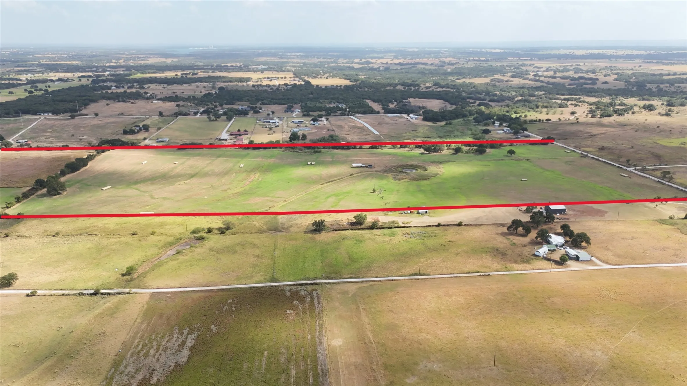 Expansive rural acreage featuring open fields, scattered trees, and distant structures