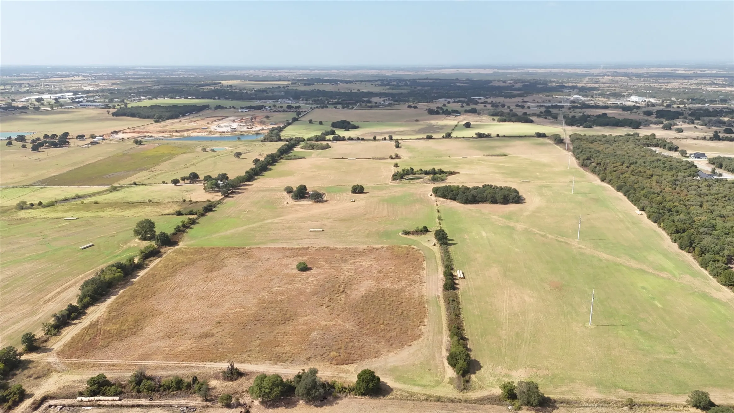 Expansive land parcel featuring open fields and mature tree lines