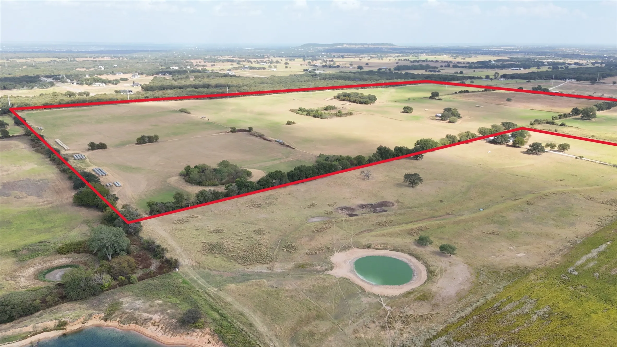 Expansive land parcel featuring a natural pond, scattered mature trees, and solar panels